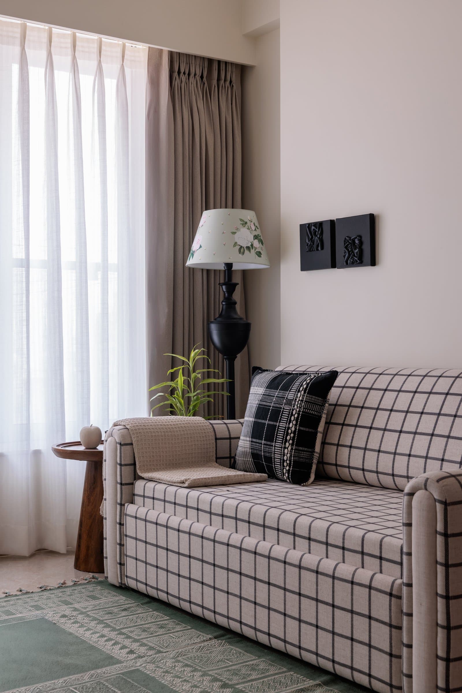 A guest room with a grid-check sofa, botanical lampshade, and green woven rug carves out its own identity