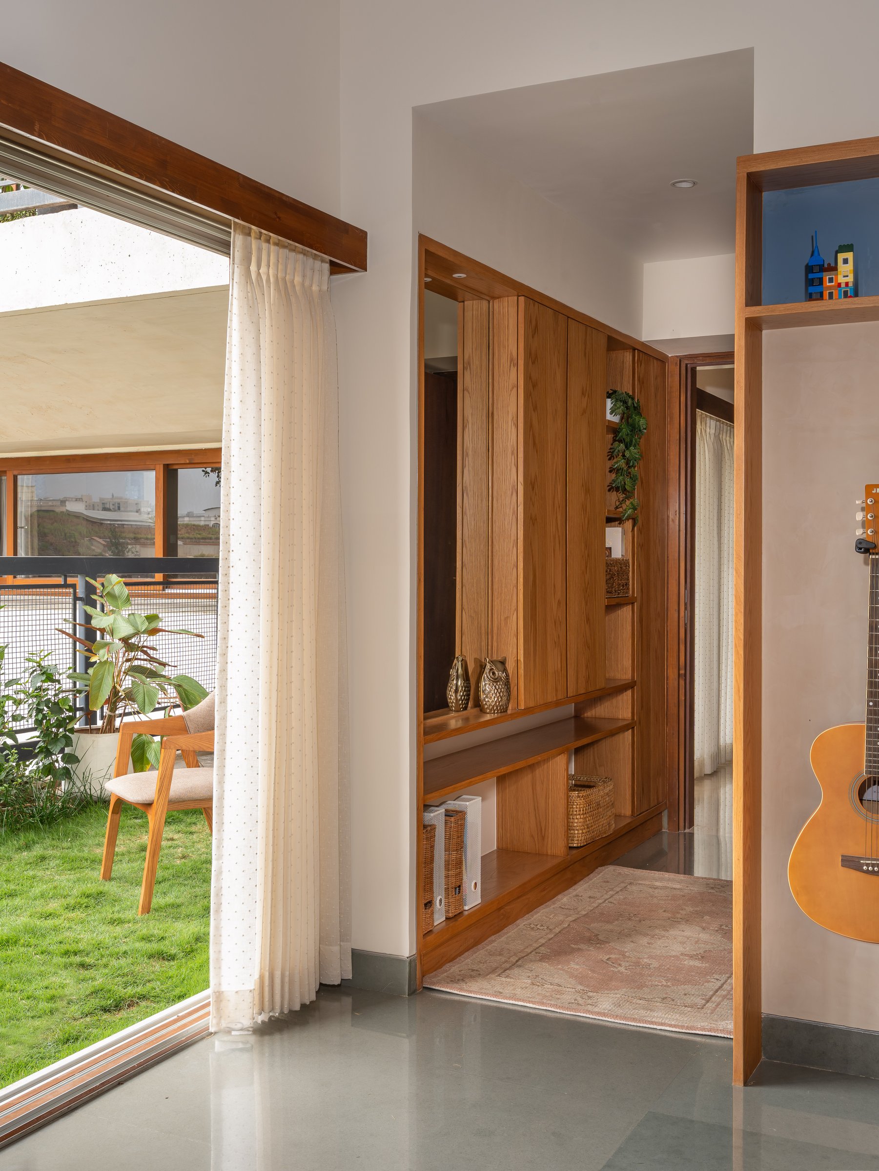The passage: floor-to-ceiling glazing opens to a grass-covered terrace, keeping the boundary between interior and green genuinely porous