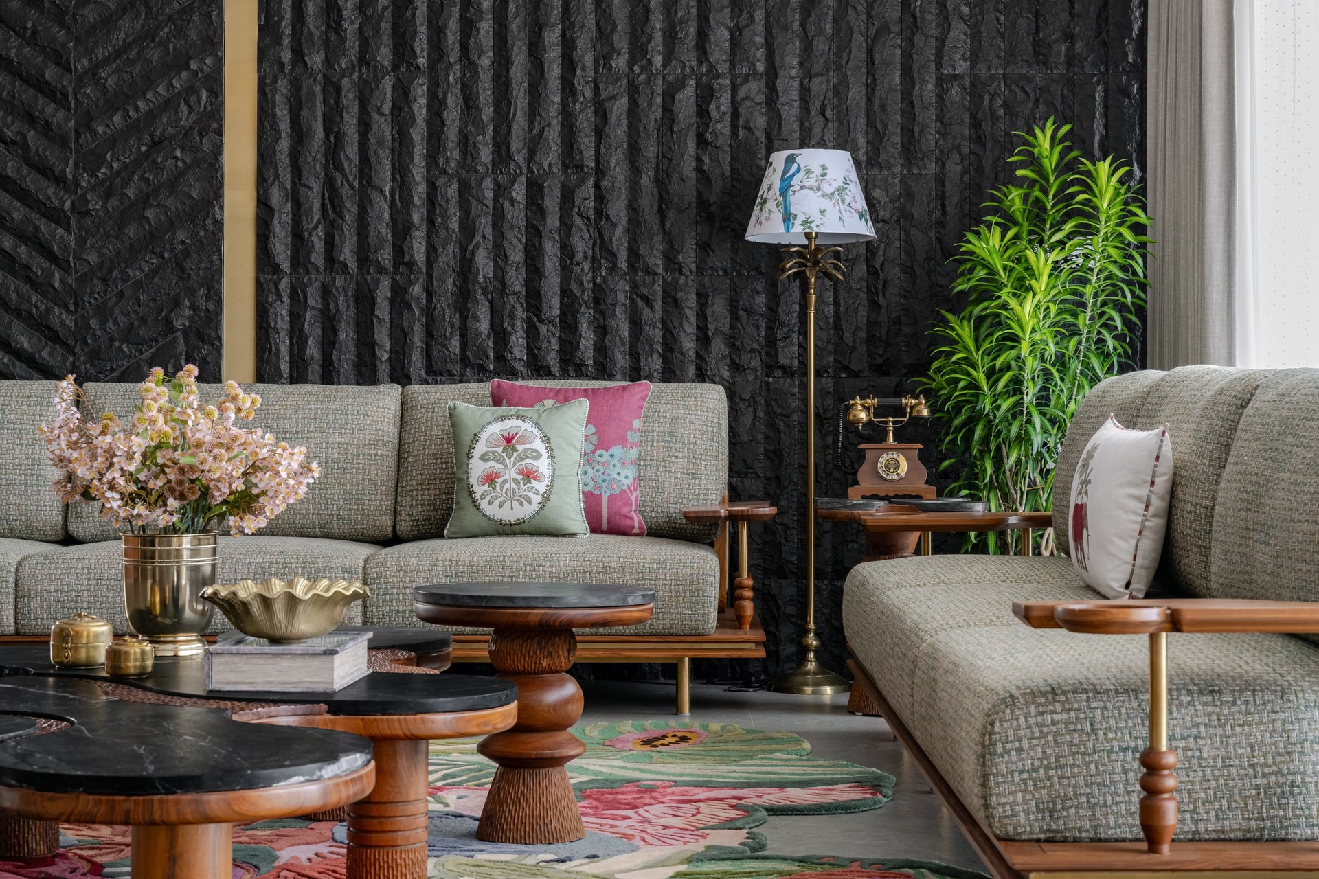 Sofas against the textured stone wall, where printed cushions drawn from Mughal and Gujarati floral traditions add controlled colour