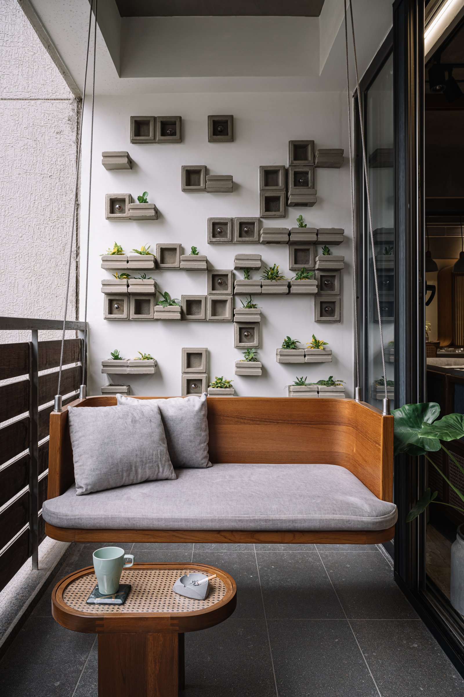 The balcony's modular concrete planter wall and timber swing seat, the home's quietest corner