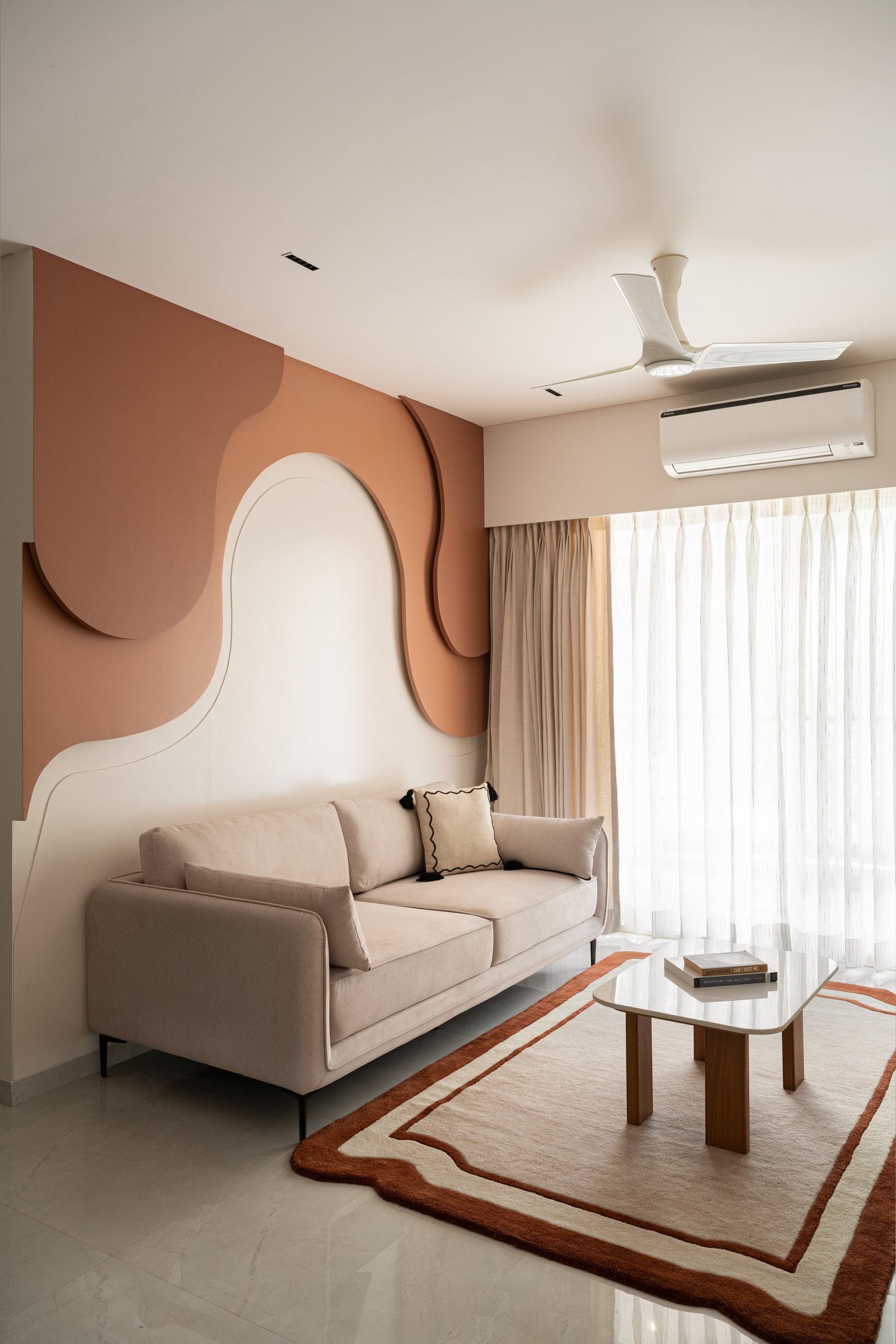 The sofa and rug defer to the sculptural wall, letting one element carry the room's entire visual weight