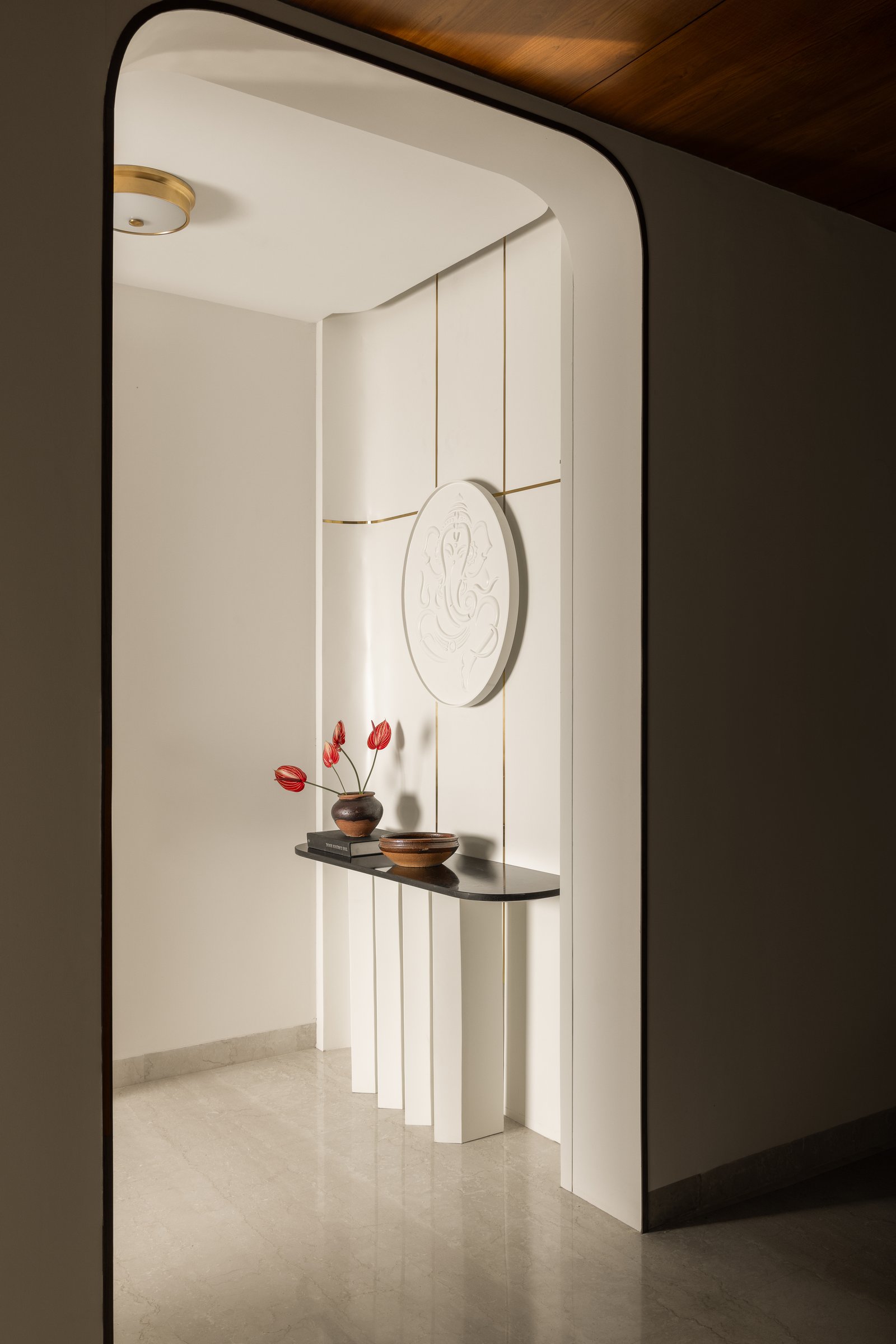 The entryway: a brass-grooved panel and carved relief medallion establish the villa's vocabulary of restrained precision