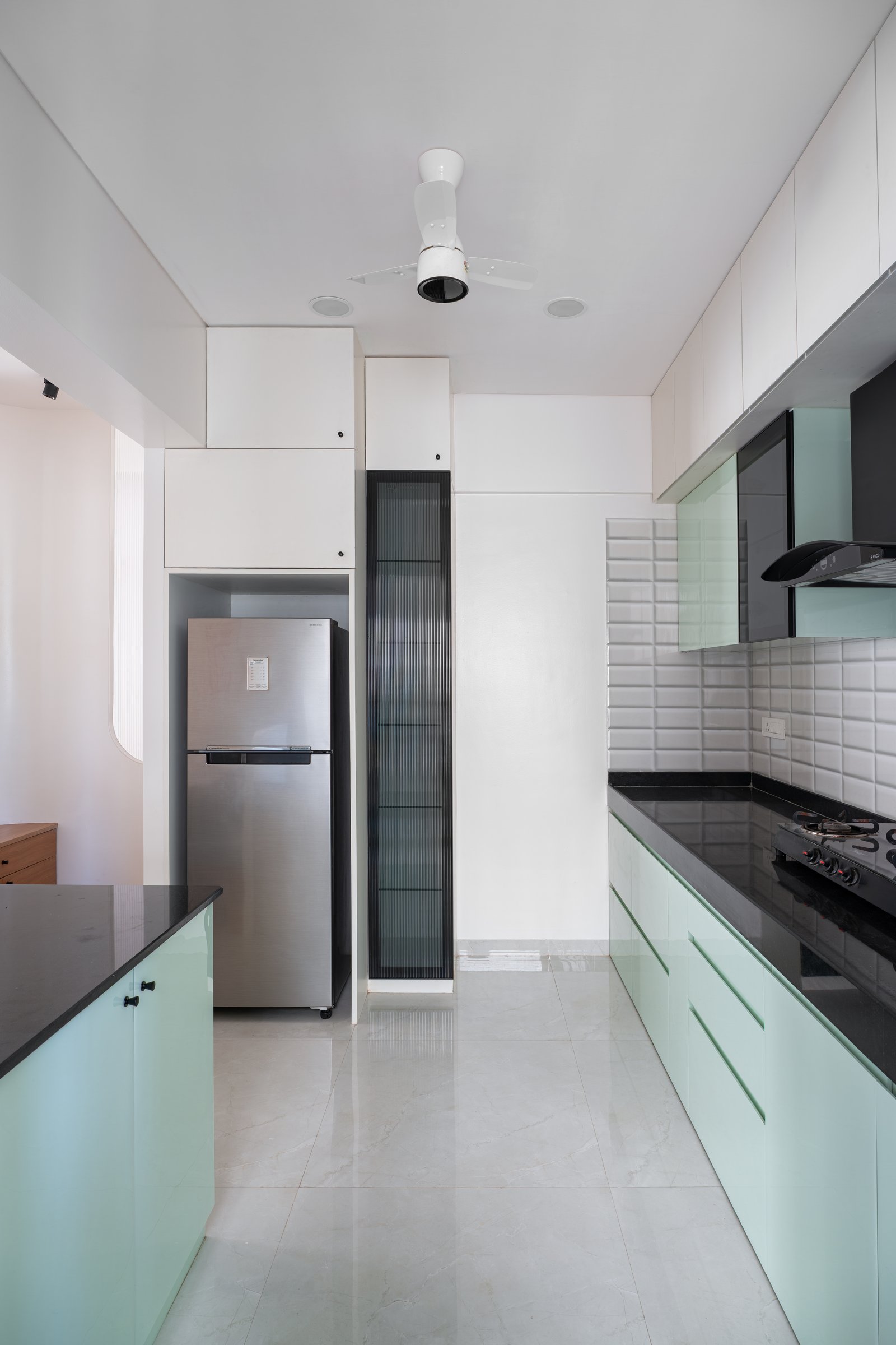 Inside the kitchen, where the parallel layout and a tall fluted-glass display unit maximise a narrow footprint