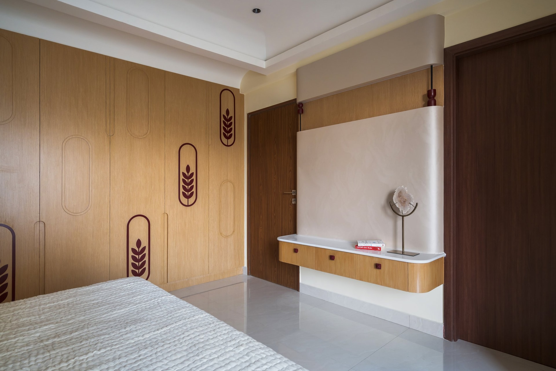 The master bedroom's wardrobe wall, where botanical inlays within capsule-shaped outlines introduce pattern through joinery