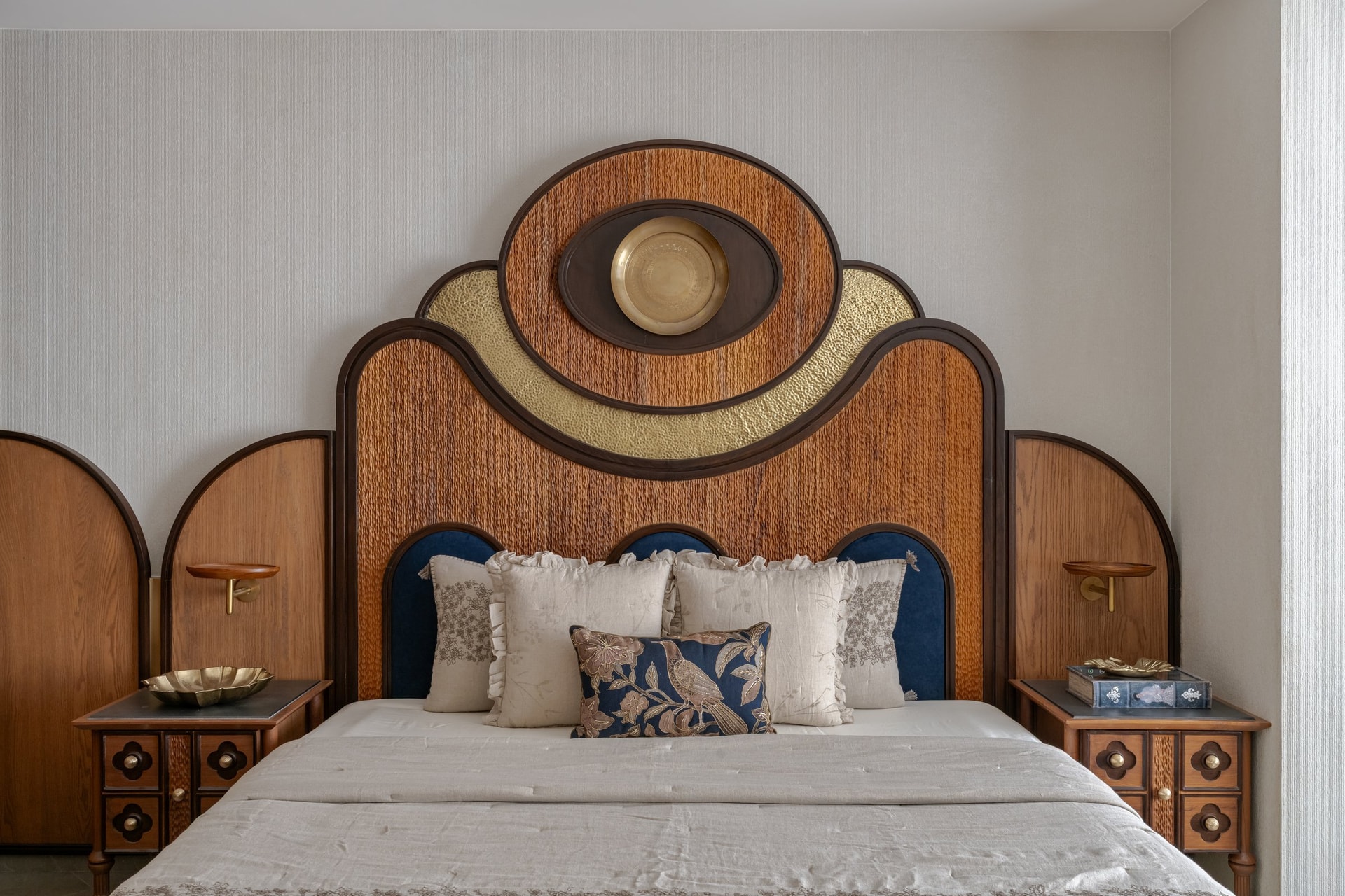 Wing A's master bedroom headboard: layered arches of carved timber and hammered gold, crowned by a brass medallion
