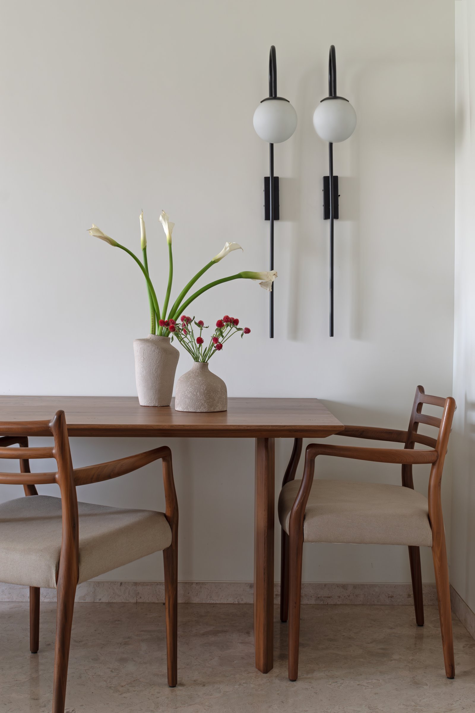 The dining corner, where an empty wall behind the teak table reads as a deliberate breath rather than a missed opportunity