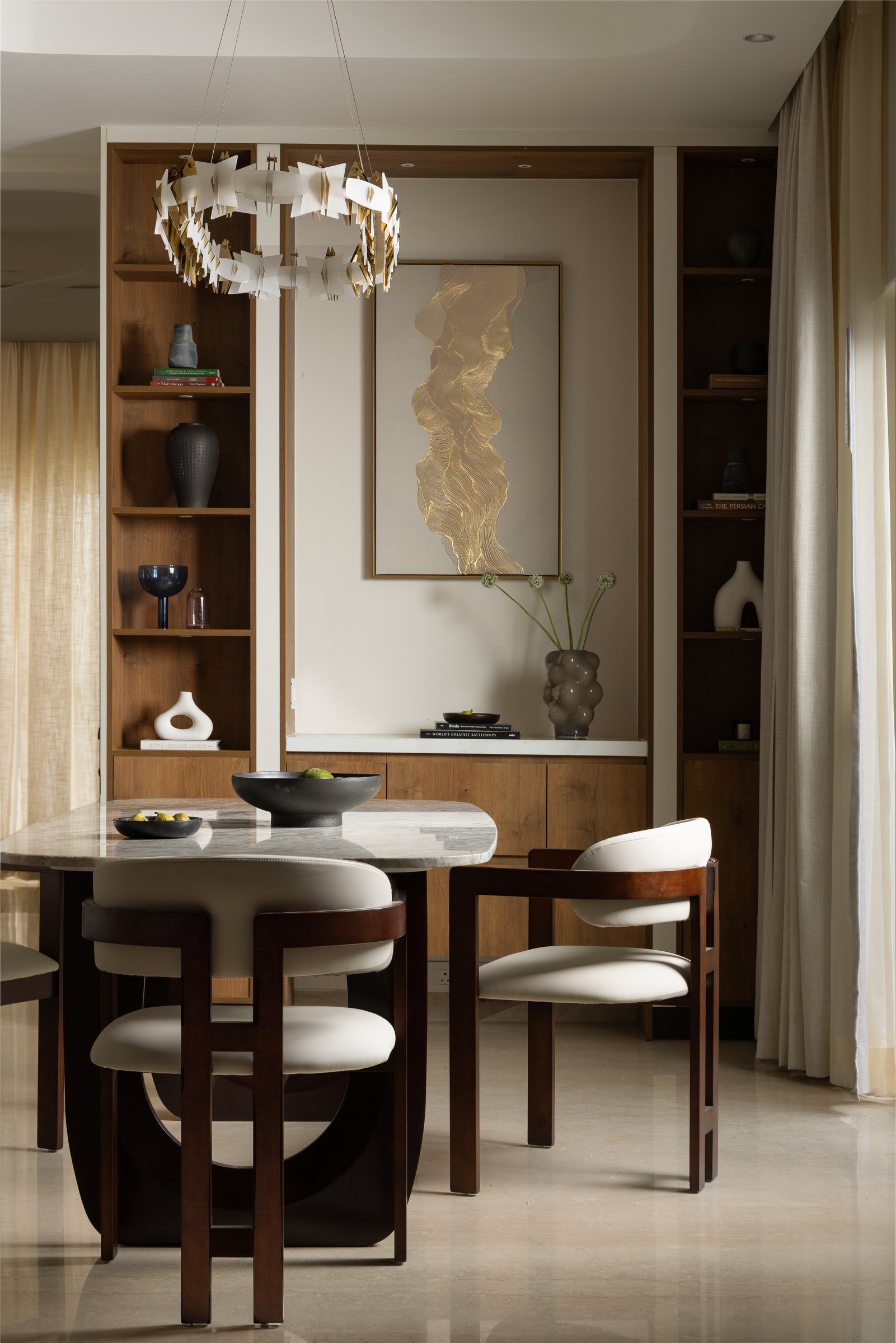 The dining area, framed by timber cabinetry and a sculptural gold-toned pendant