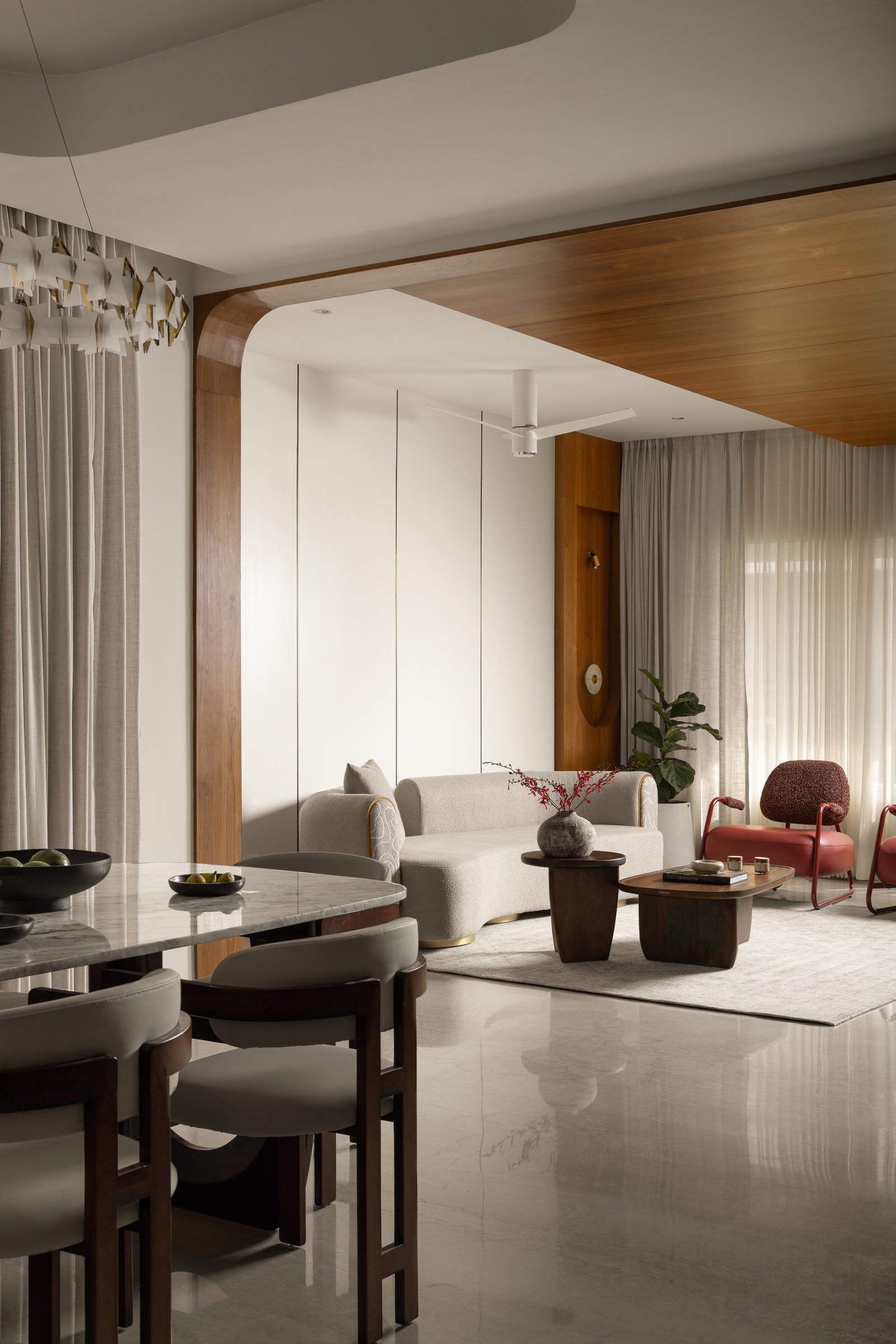 The formal living and dining zone, where a timber ceiling distinguishes the seating area from the white plaster plane above the dining table