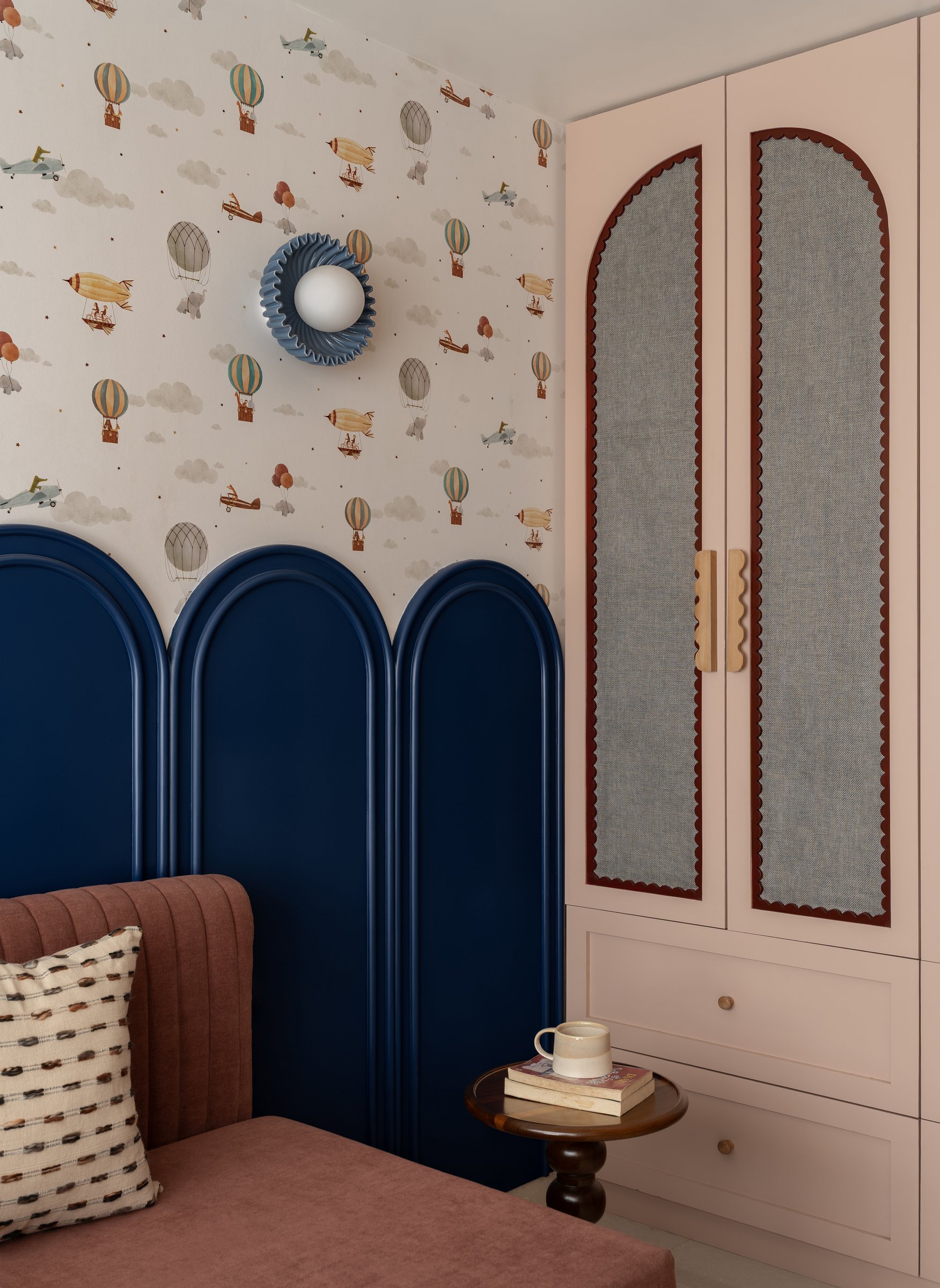 The children's room commits fully to character, with vintage-aviation wallpaper and a navy arched dado