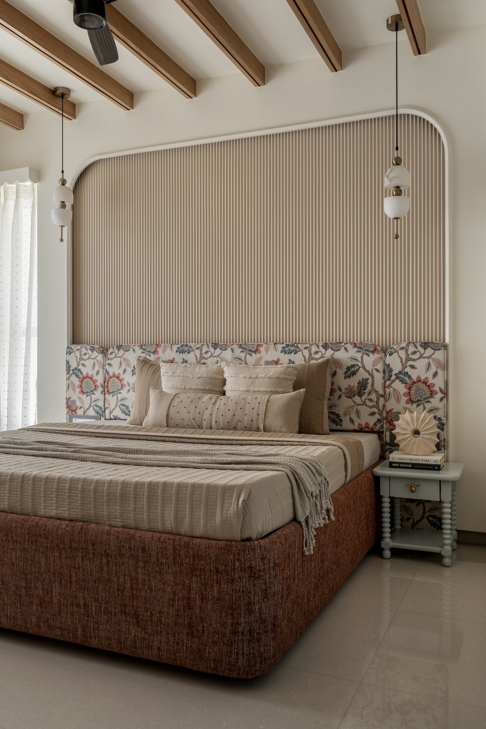 The master bedroom: a fluted oat-toned arch, jacquard side panels, and a rust chenille bed base