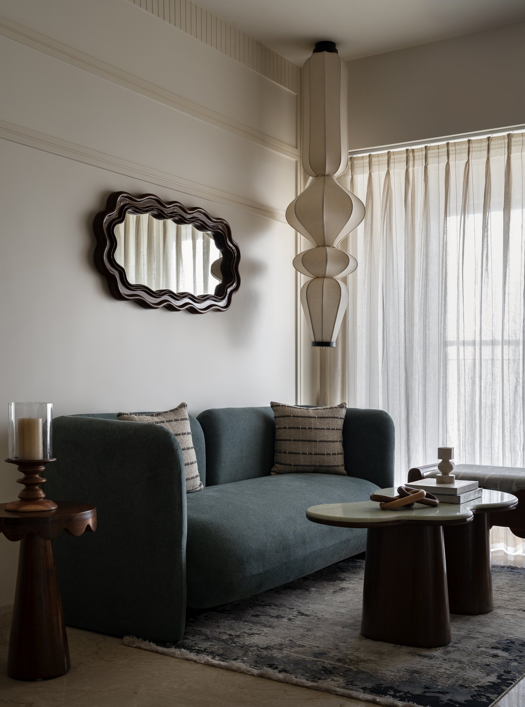 A teal settee, pleated lantern pendant and scalloped mirror compose the seating zone with three distinct curves in conversation