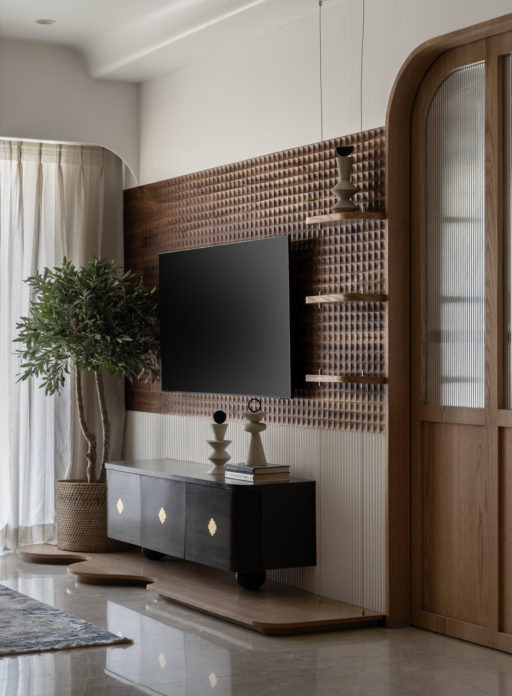 The living room's hand-tooled grid wall, paired with reeded cream panelling and a blackened console with brass quatrefoil pulls