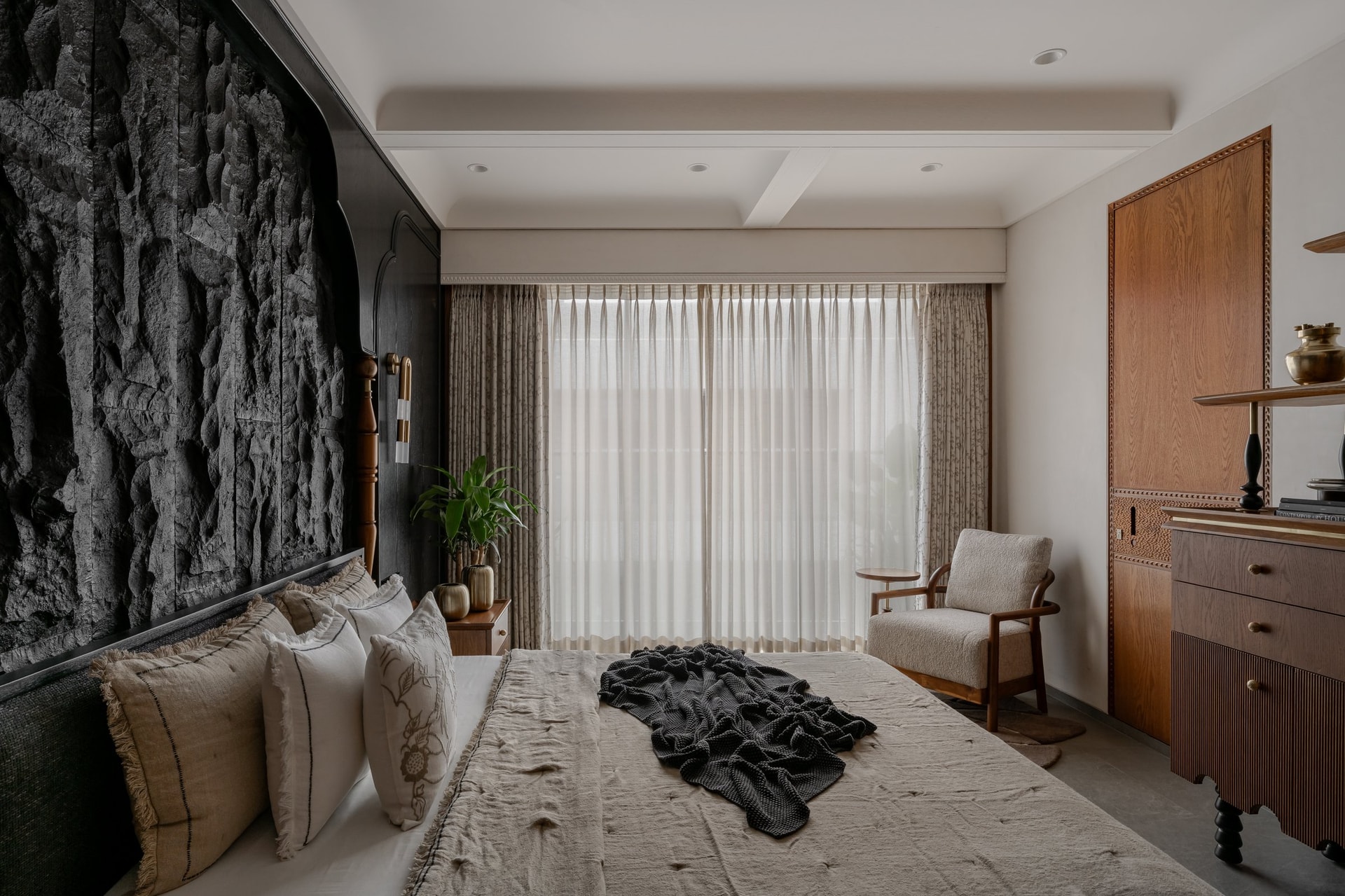 Natural light tempers the dark stone enclosure in the grandparents' room, the timber sideboard providing grounding warmth