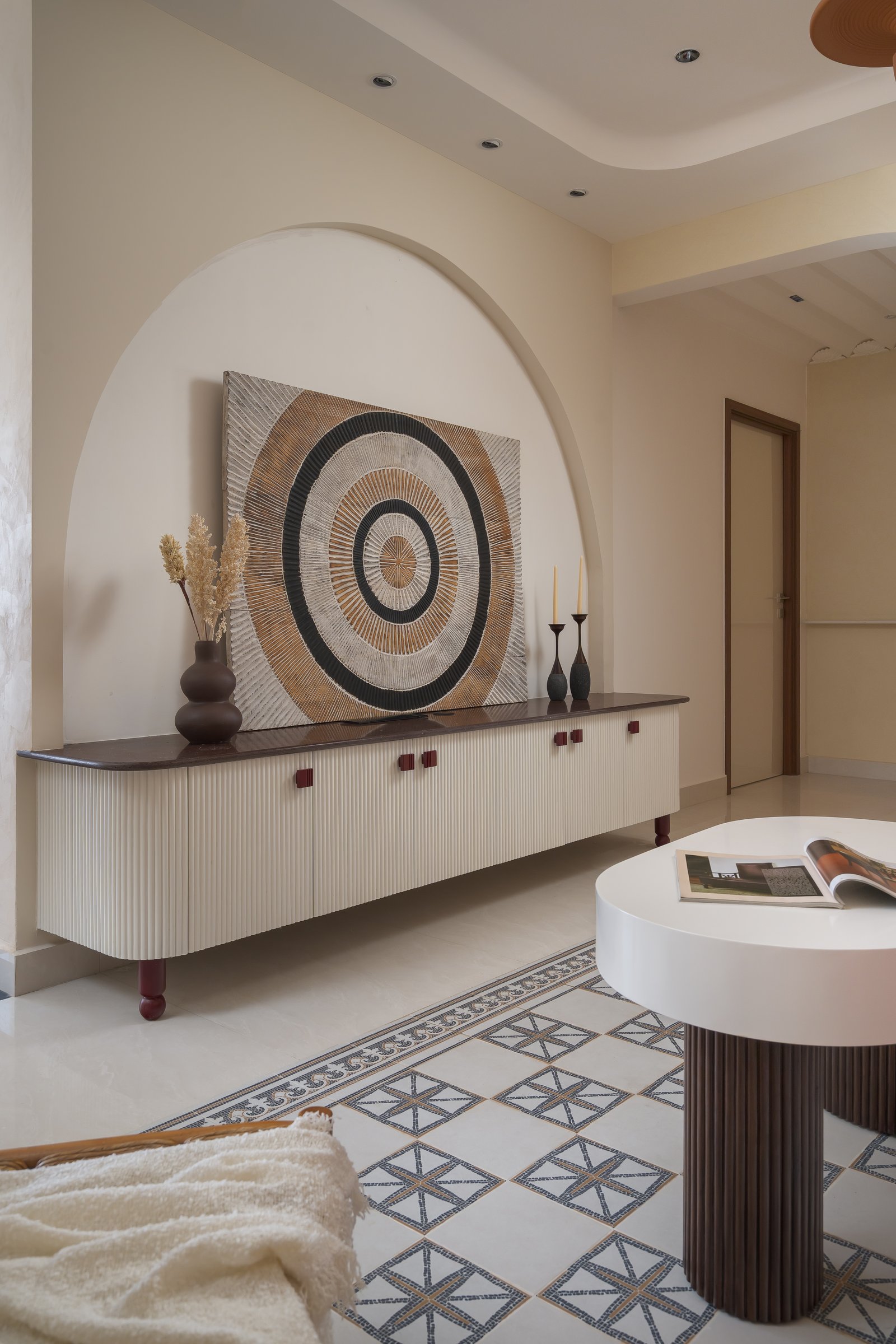 The living room console within its arch, where concentric artwork and fluted cabinetry reinforce the home's circular motifs