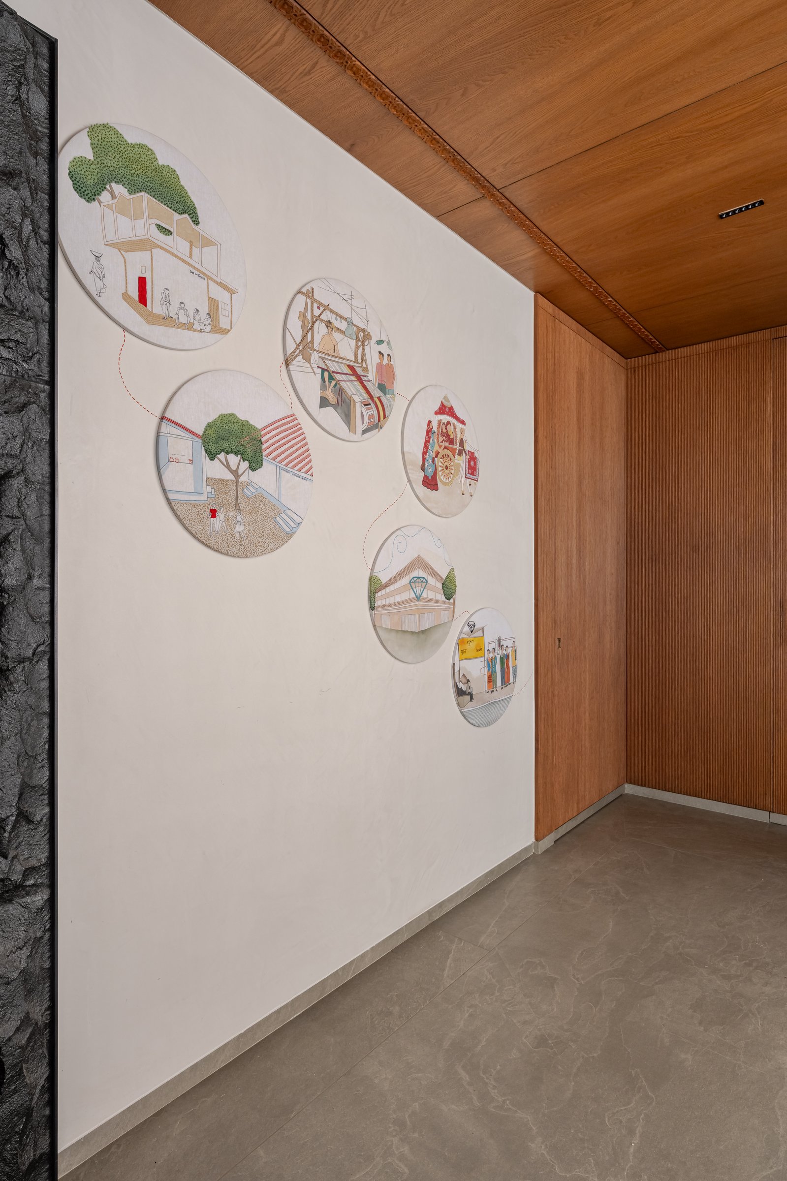 The family corridor as memoir: circular painted panels depicting ancestral homes, looms, and wedding processions
