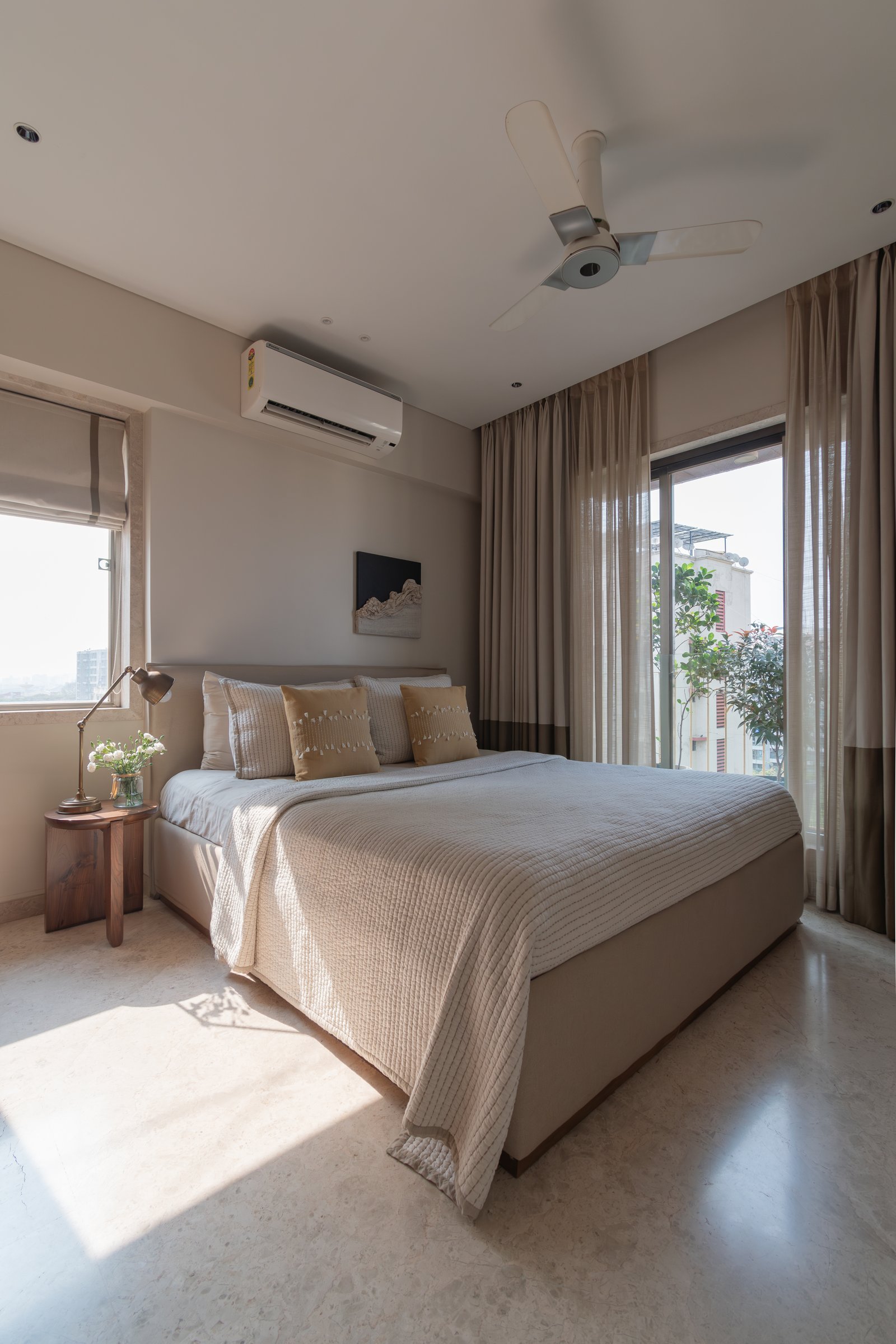 In the master bedroom, layered curtains soften Mumbai's hard afternoon light against a pared-back palette of taupe and oat