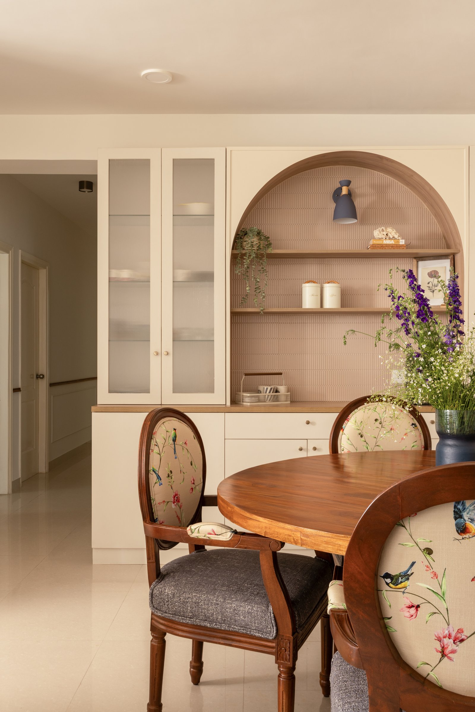 Floral medallion-back chairs and a built-in crockery unit give the dining zone its layered character