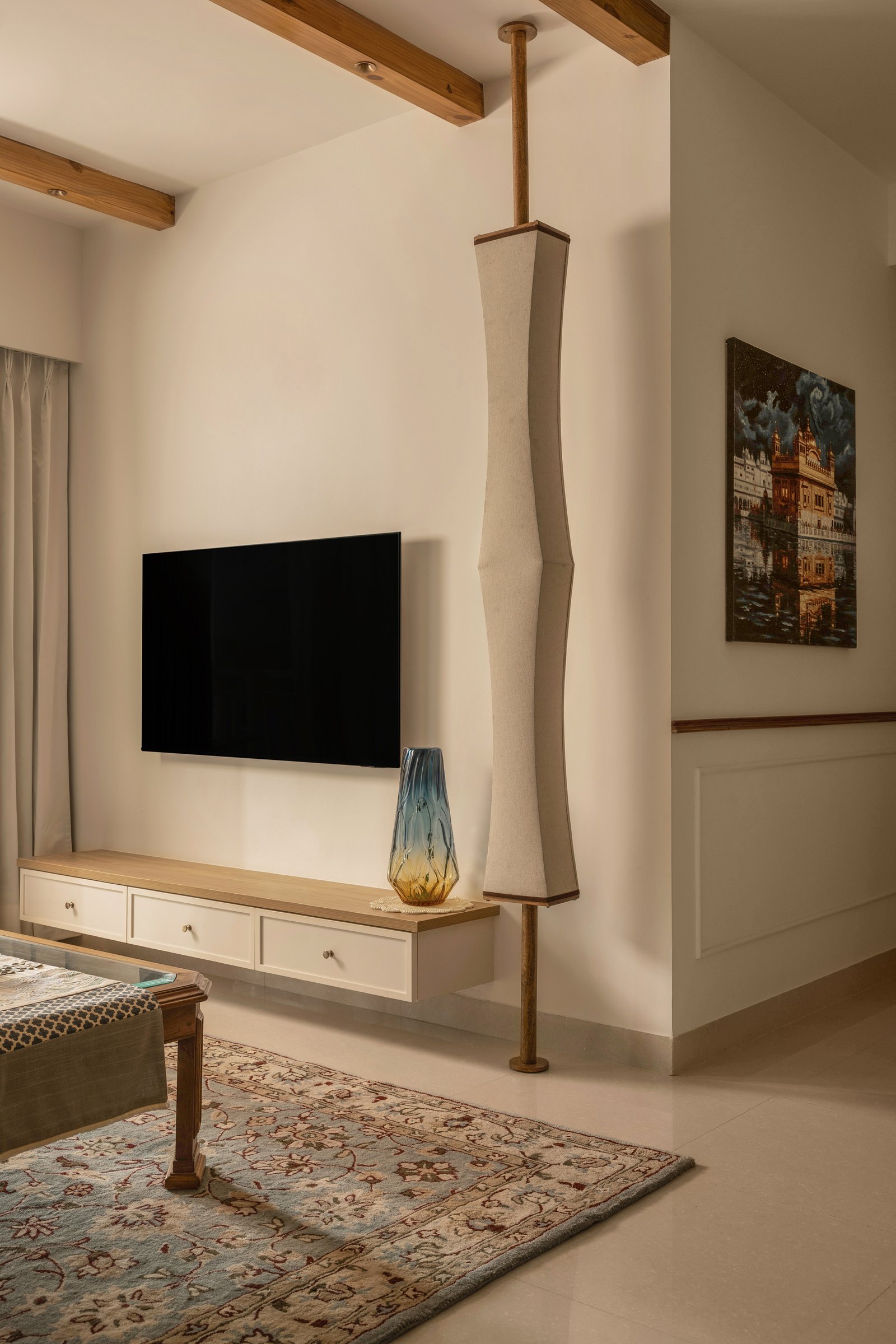 The television wall, with its sculptural linen-wrapped column softening the boundary between living and circulation