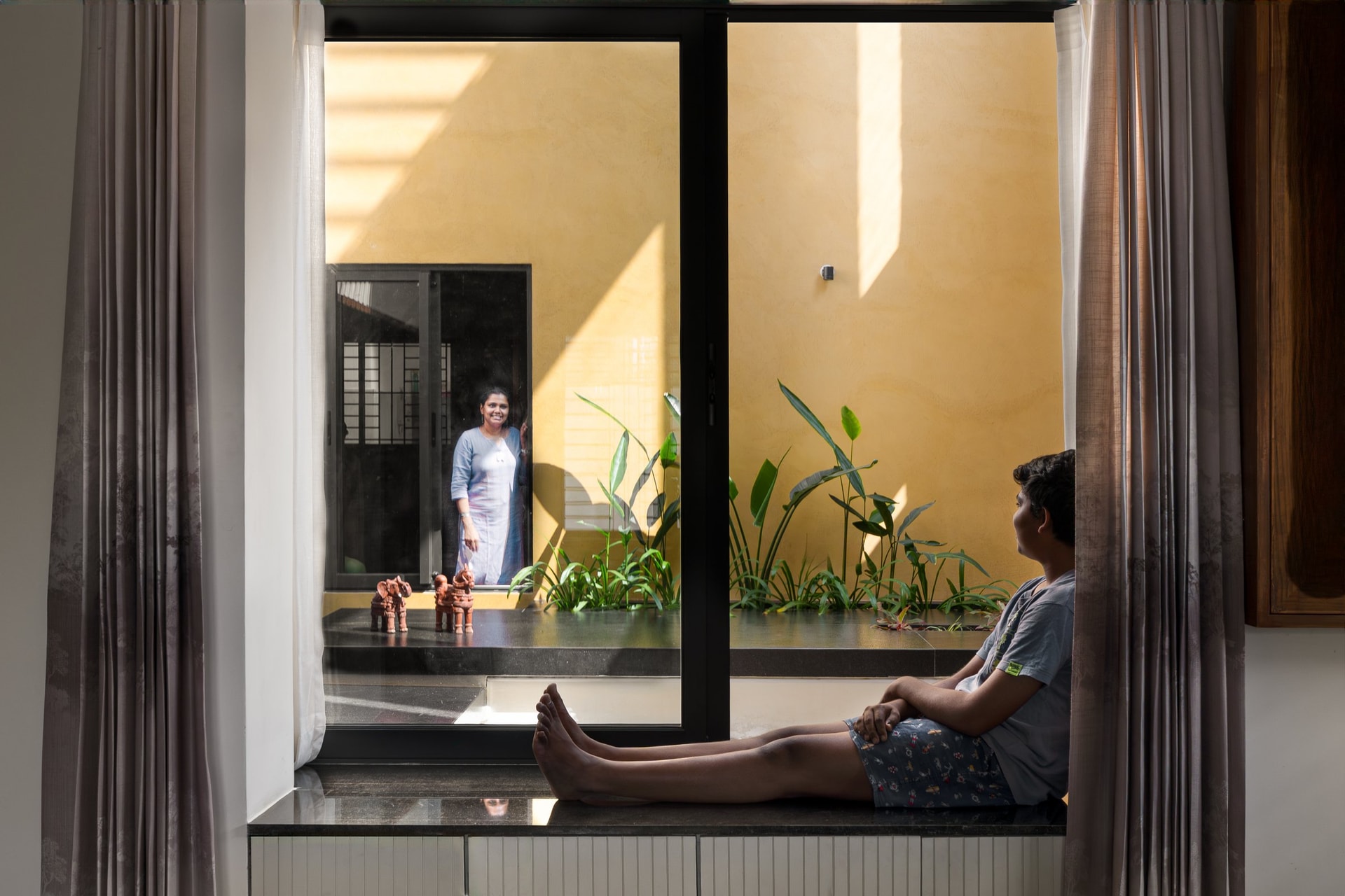 The master bedroom's bay window frames a private view of the courtyard's planting and yellow oxide wall