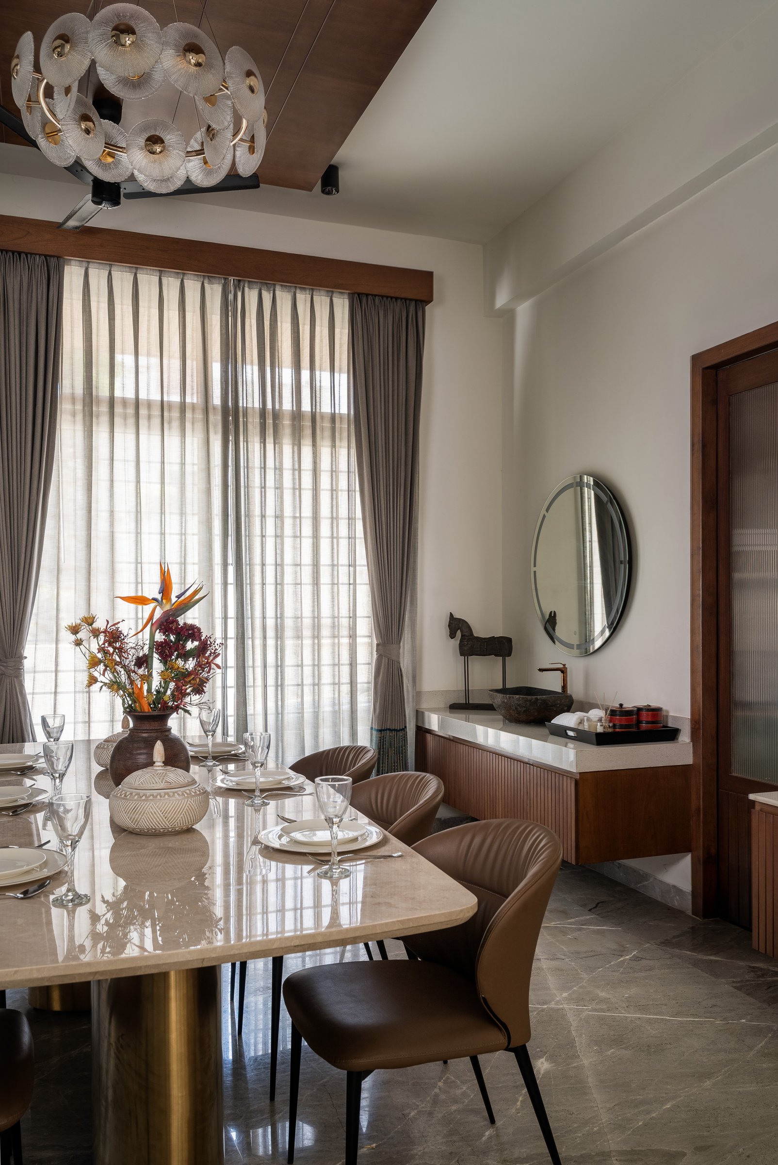 From the dining table, the floating console with its stone-bowl basin and circular mirror completes the room's hospitality