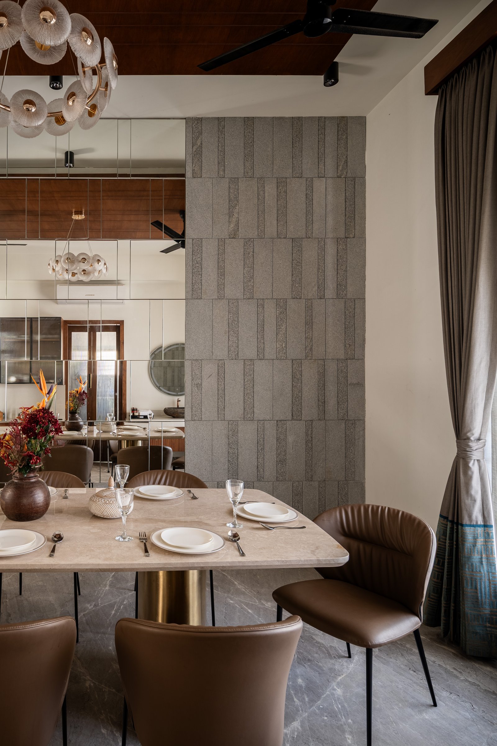 A column clad in textured granite, set into the mirrored surface, introduces mass exactly where the mirror dissolves it