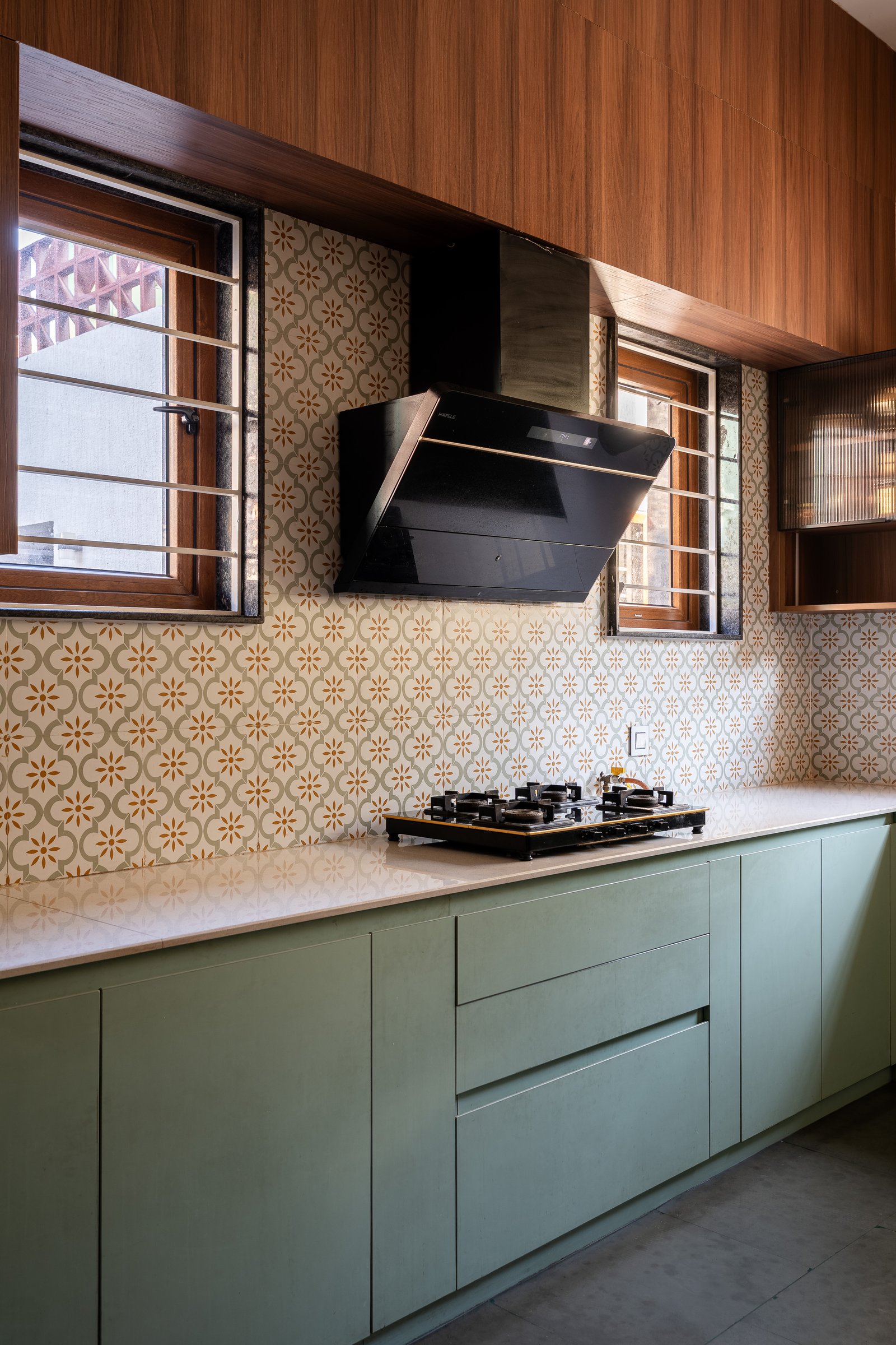 The kitchen, where sage cabinetry meets an encaustic backsplash of small ochre florals, restraint with a quiet point of view