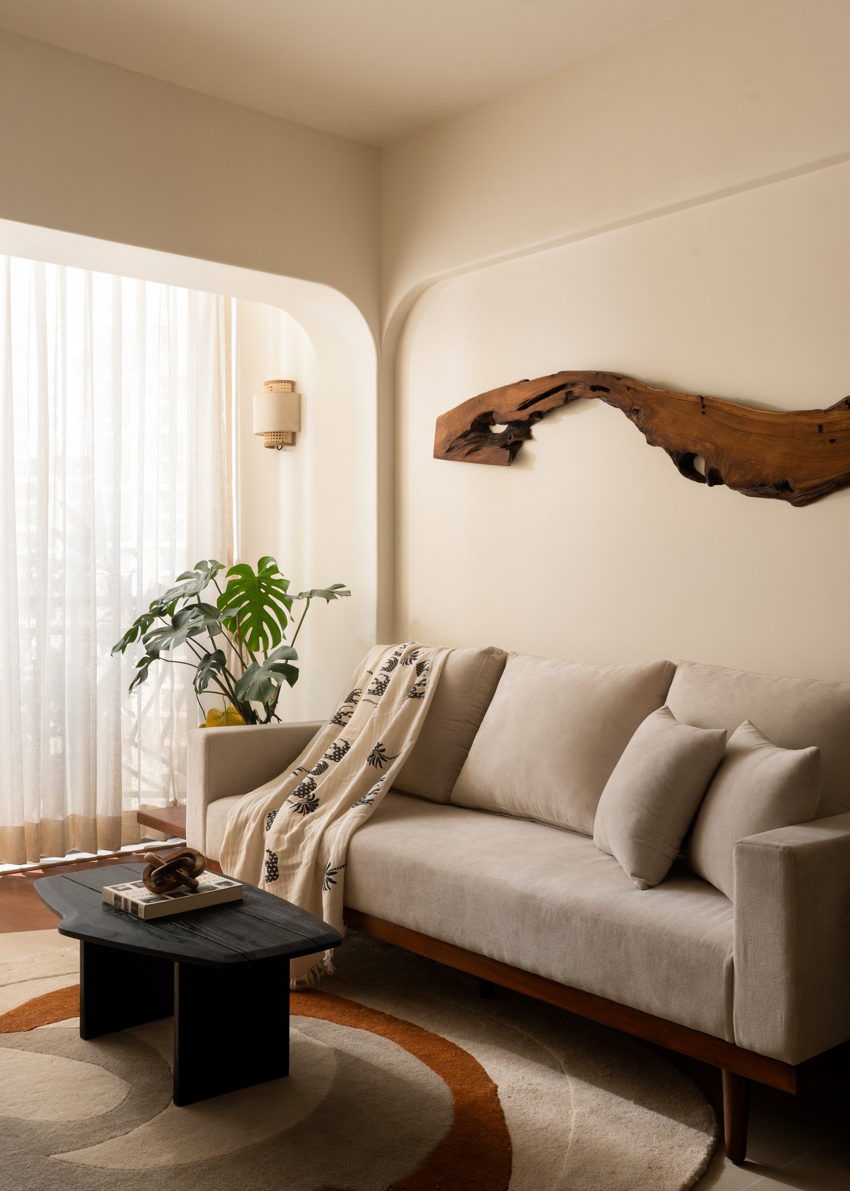 A piece of weathered driftwood becomes the living room's principal artwork, doing the work a painting might do elsewhere