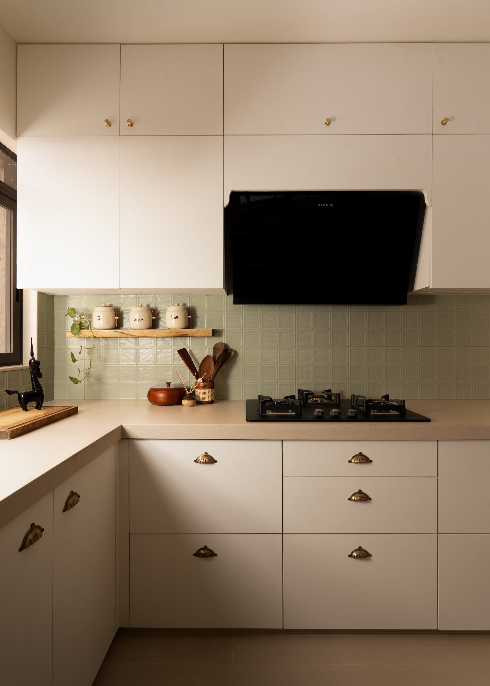 The kitchen, calm and almost monastic, with a sage-green textured backsplash