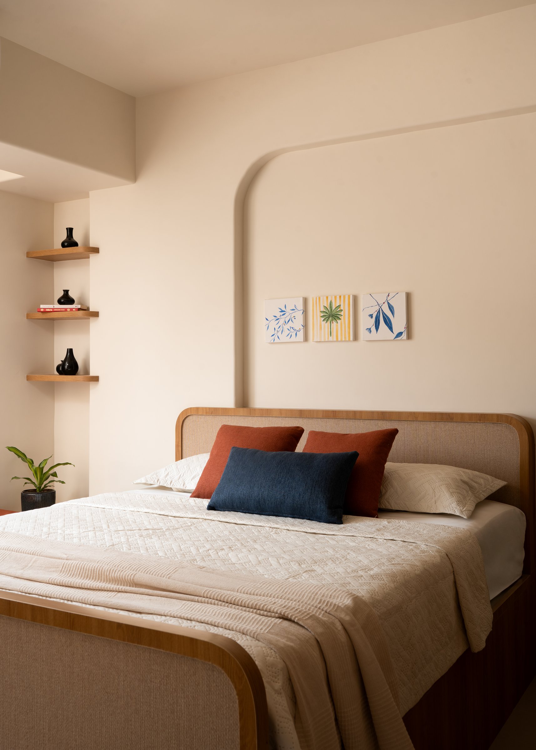 The cane-backed bed set against a curved plaster cartouche, soft architecture in place of wallpaper