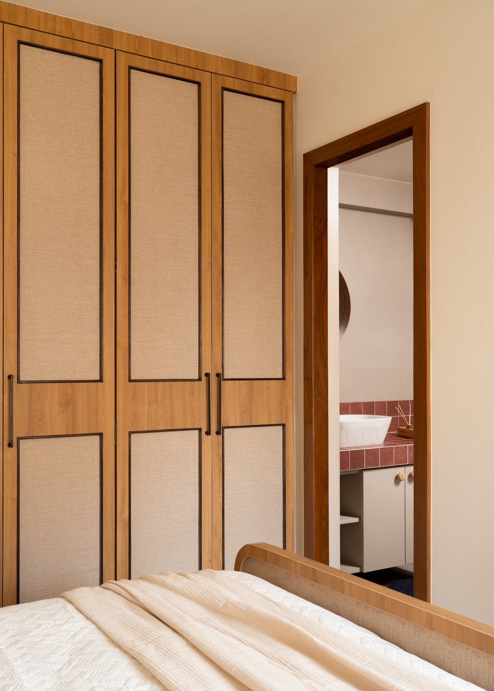 A doorway between wardrobes opens onto the terracotta-tiled master bath