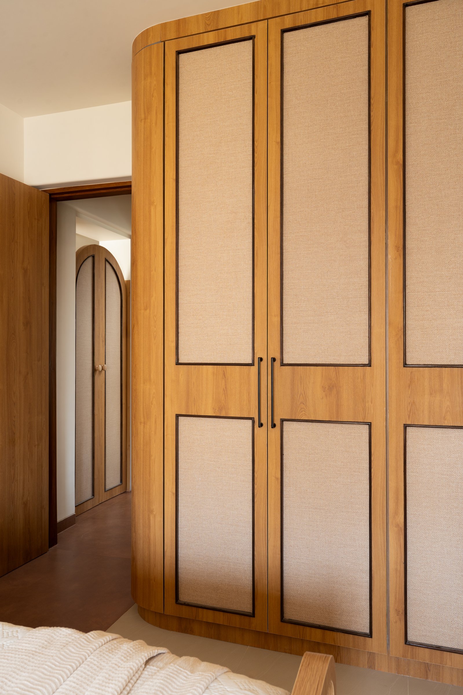 Curved at the corner where most cabinetry would terminate flat, the wardrobe joinery softens the room
