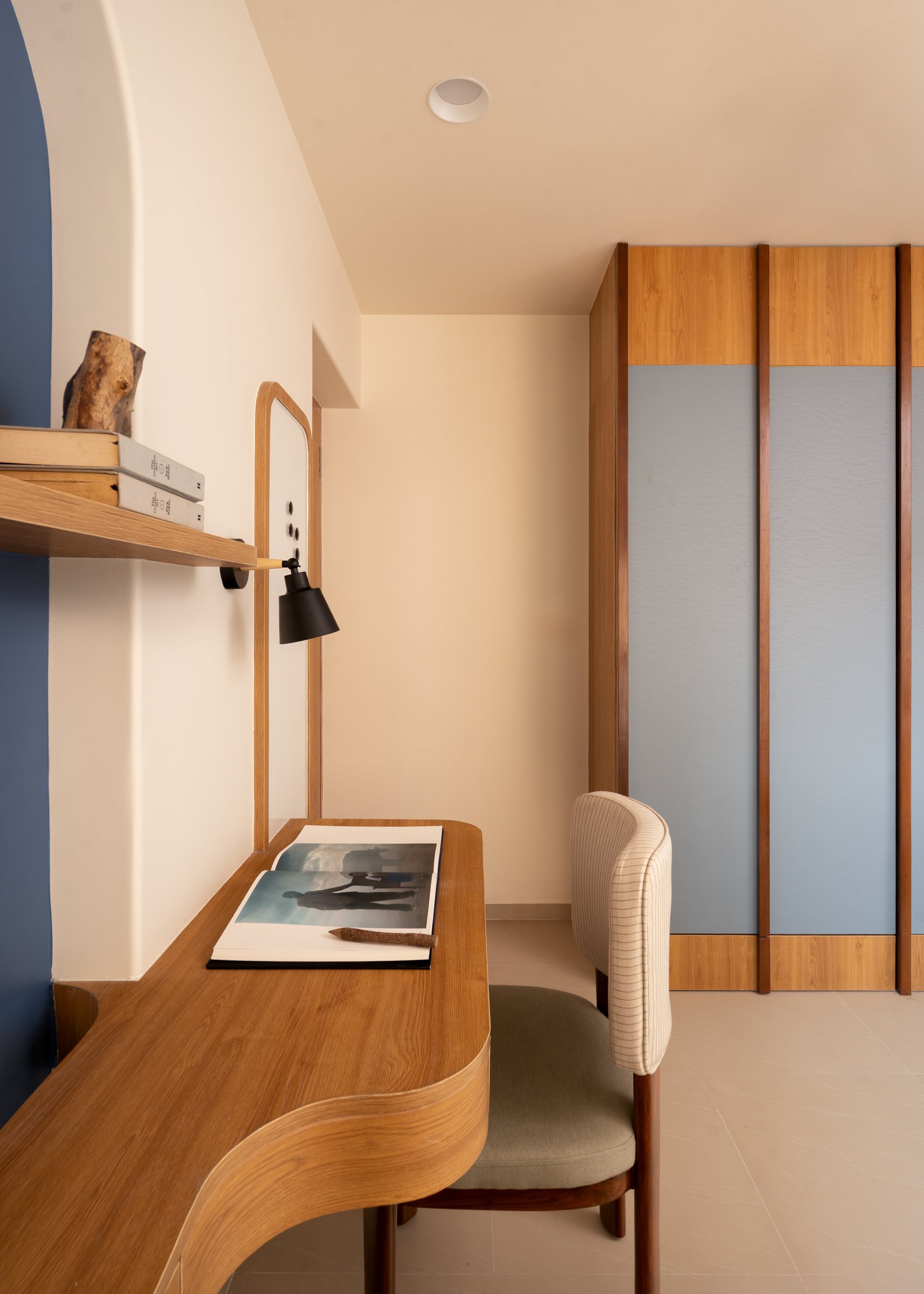 The desk curving toward the wardrobe, its softened edge avoiding a hard right-angle approach
