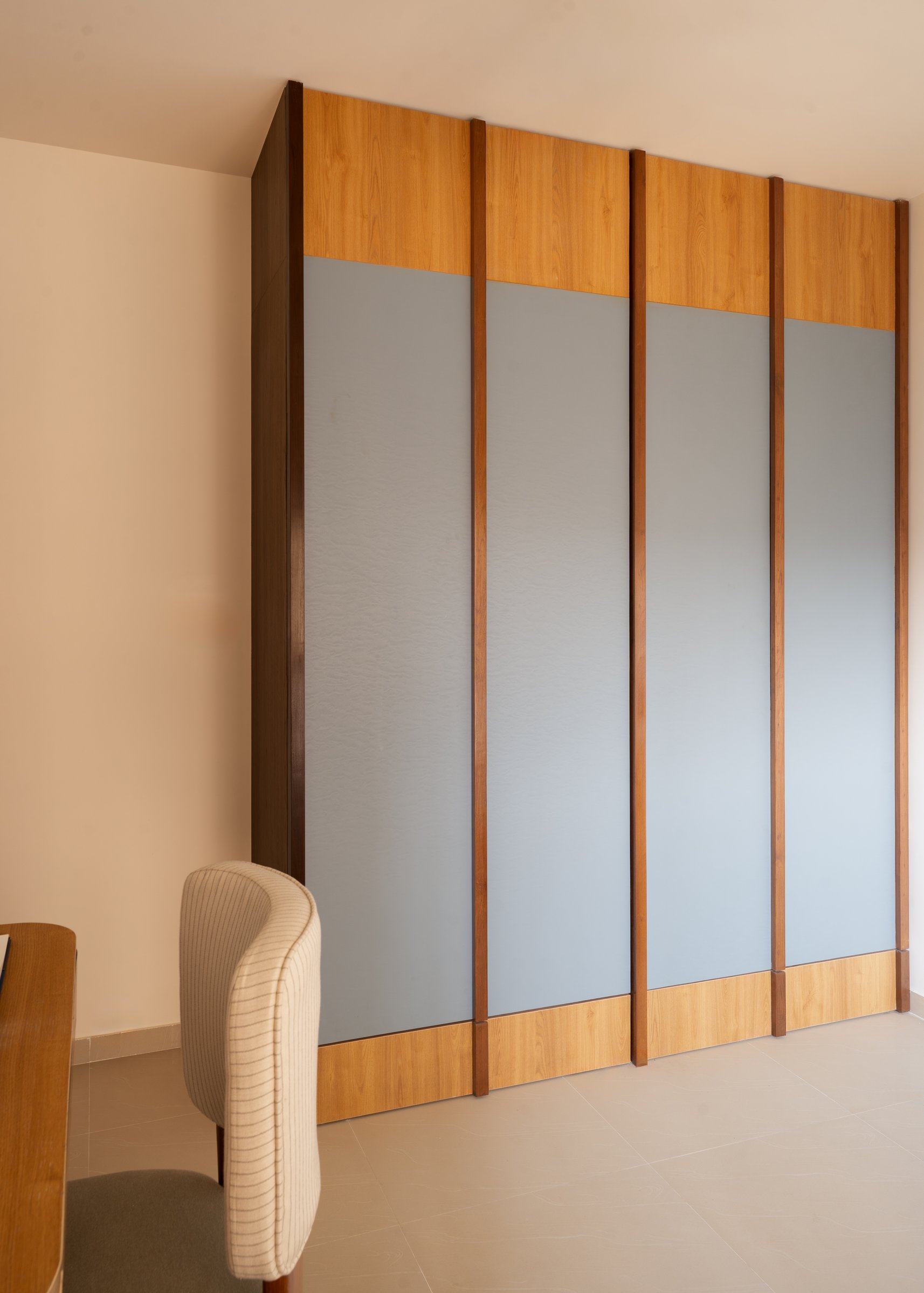 Four pale-blue panels separated by warm timber stiles, the wardrobe reads almost as architecture