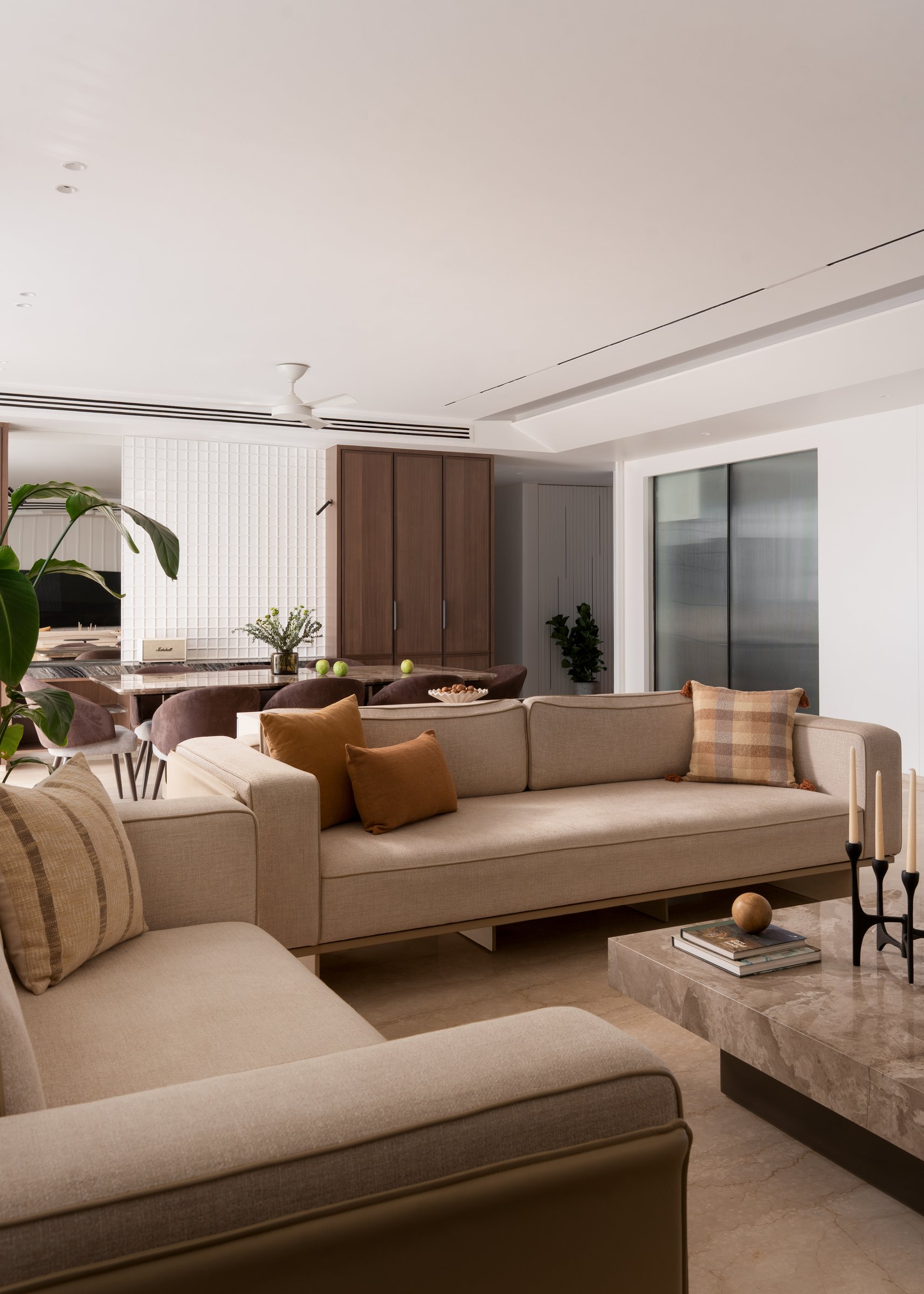 Looking back across the living room, with its linen sectional, stone coffee table, and blackened-metal candelabra