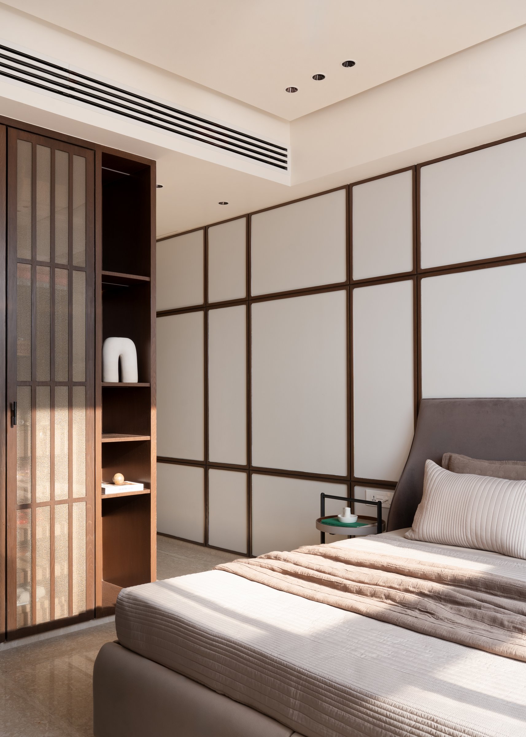 The master bedroom, where a grid of linen panels framed in walnut references shoji geometry without quoting it