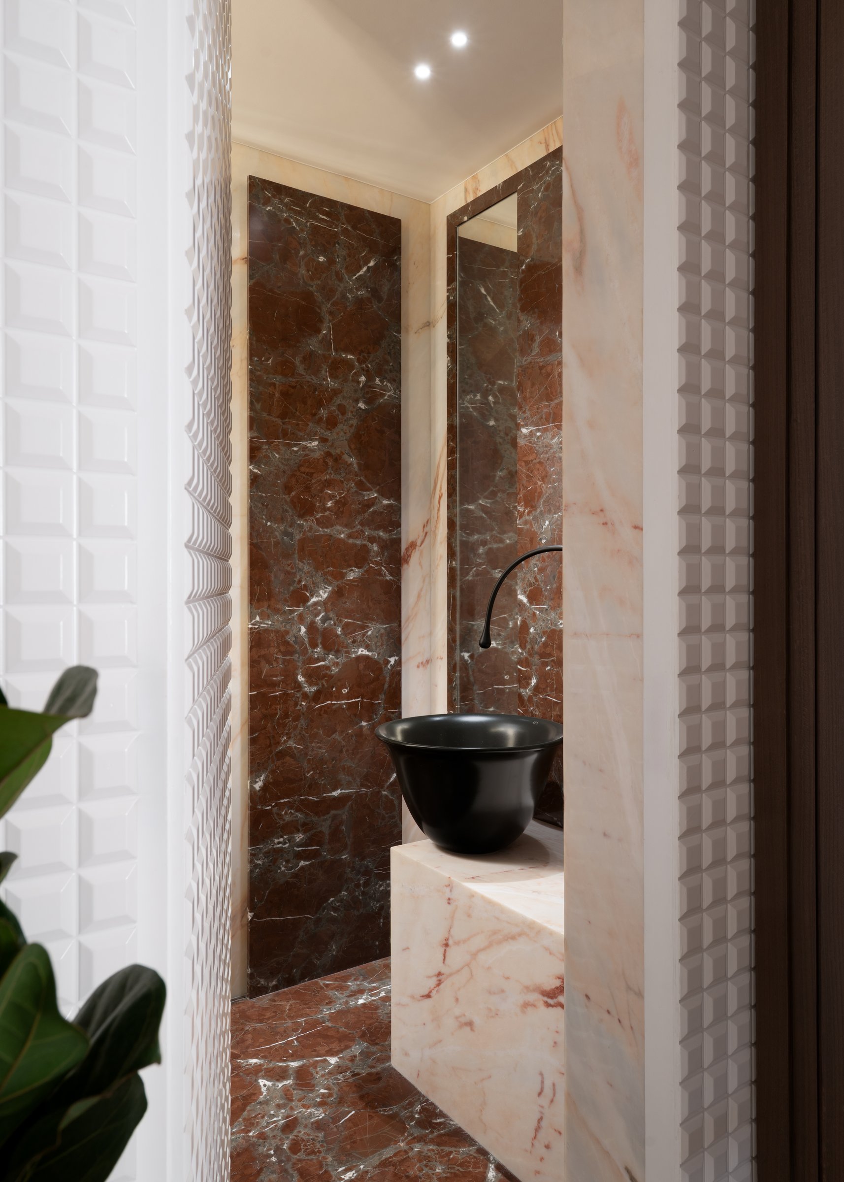 From the threshold, the powder room frames warm marble through a sculpted white tile surround