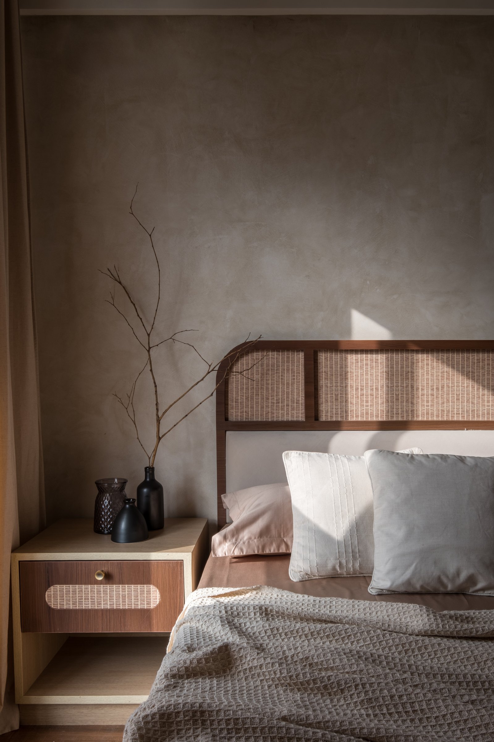 The bedside detail, where cane joinery and plaster light come together in their gentlest form