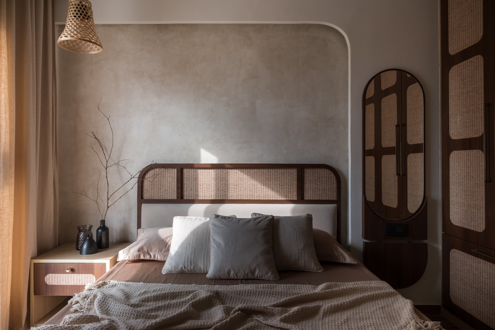 The master bedroom: a cane-and-timber headboard set against softly plastered wall, framed by a curved moulding