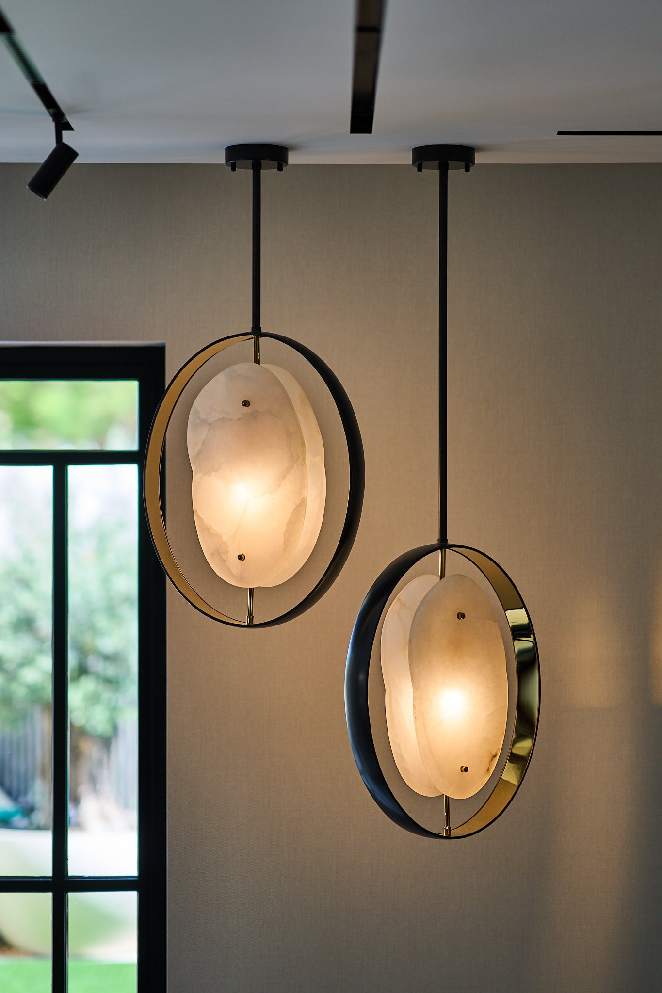 A pair of alabaster pendants, lit from within, that read more as sculpture than as illumination