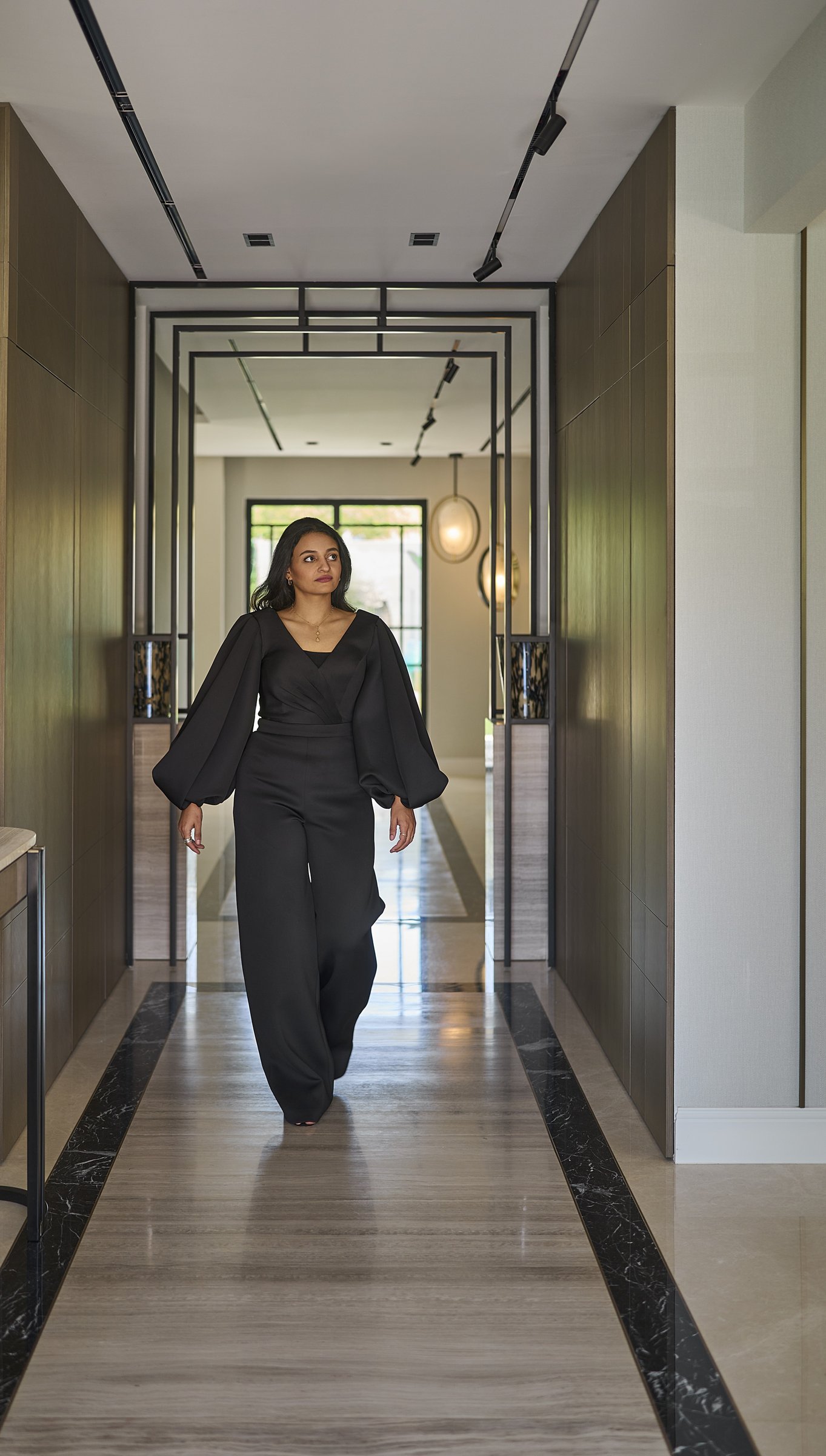 The corridor as architecture: slim black metal portals draw the eye along an axis of polished stone
