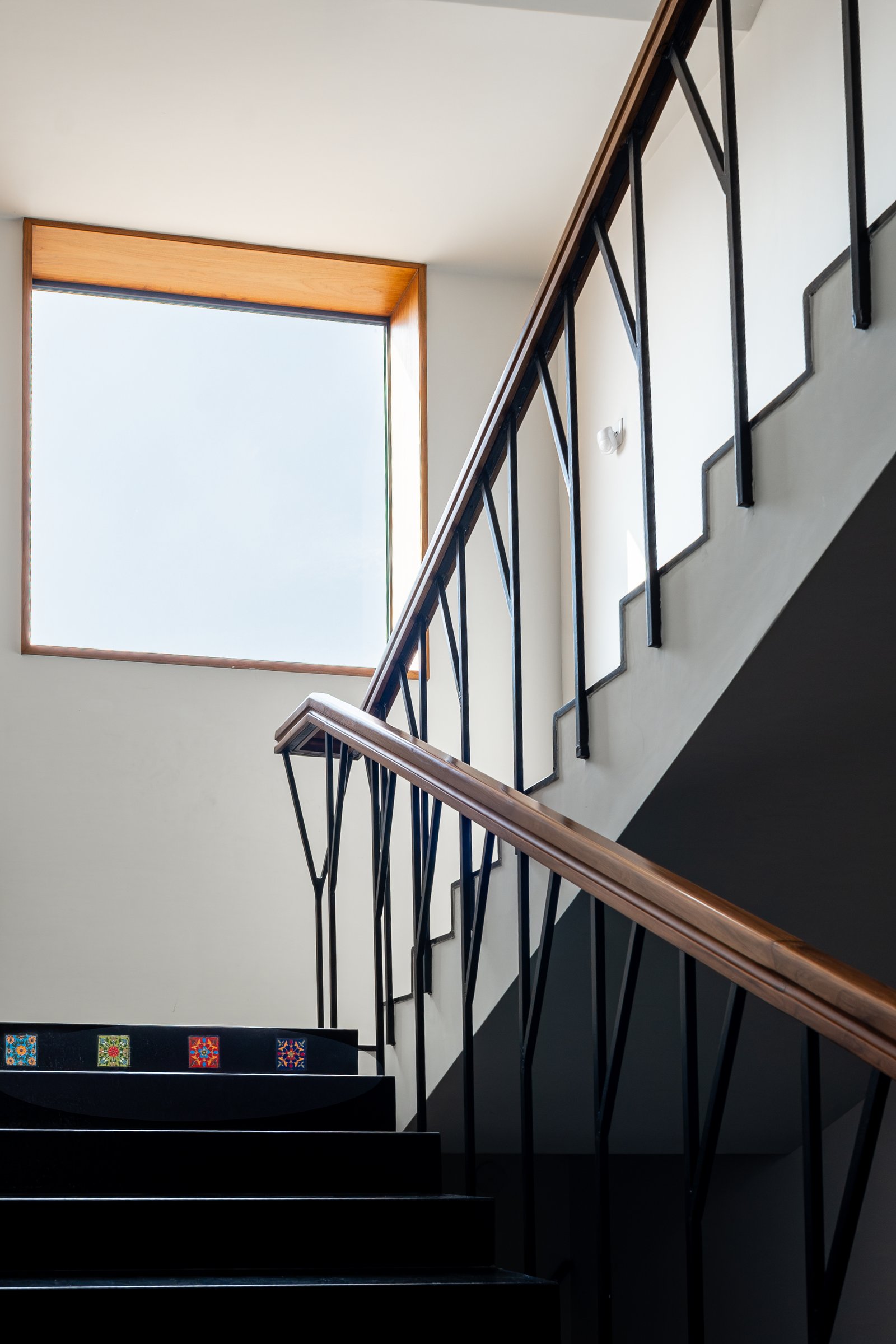 The staircase: black granite treads with handmade tile inlays and a Y-motif railing drawn from the couple's initials