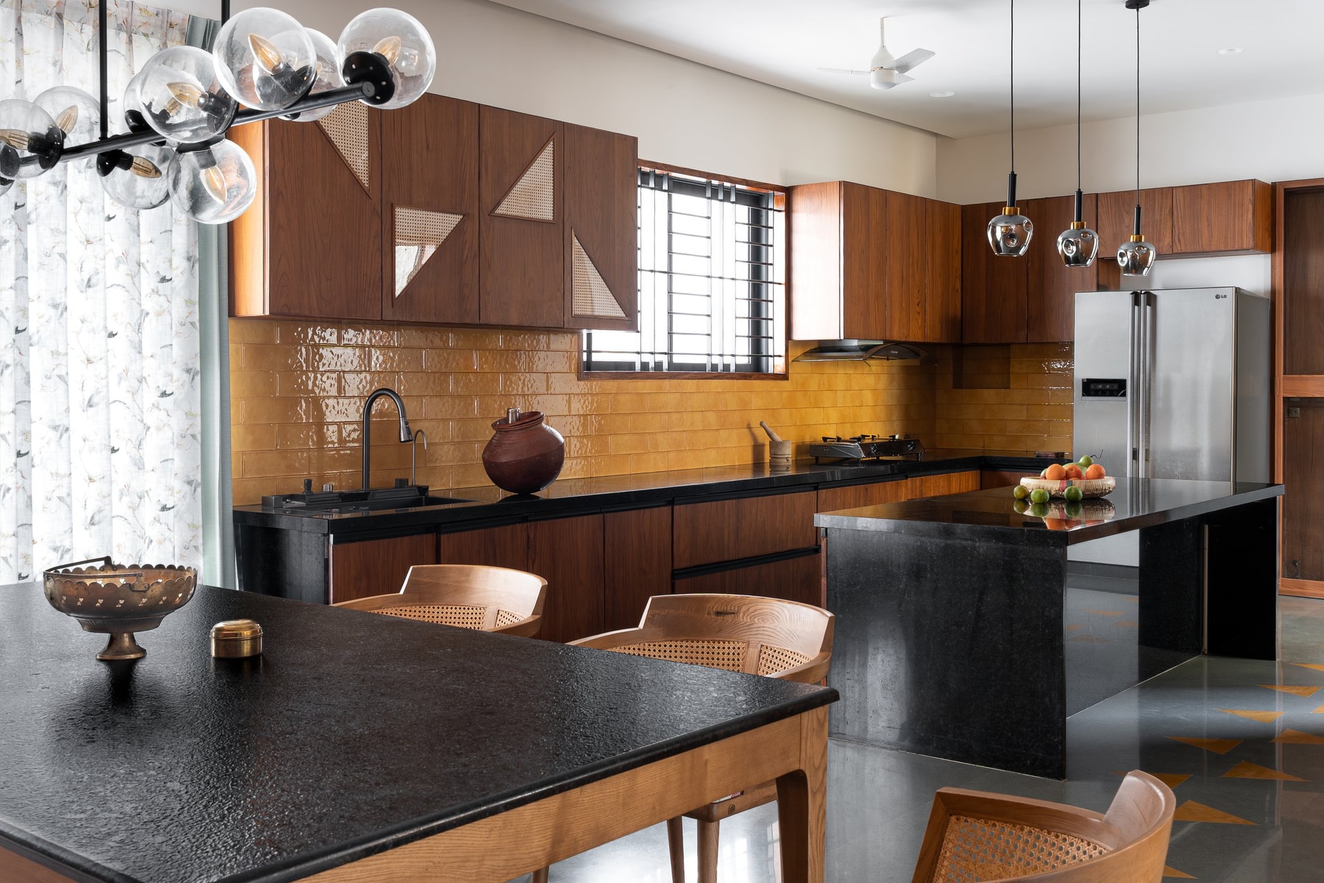 Kitchen and dining united by the black granite island, with warm-toned backsplash tiles behind