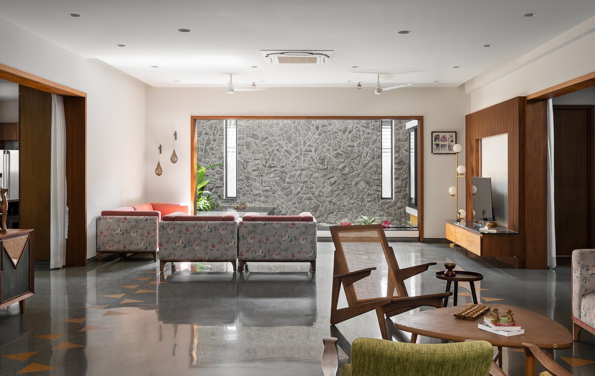 The living room, looking toward the courtyard's rubble masonry wall through a generous timber-framed opening