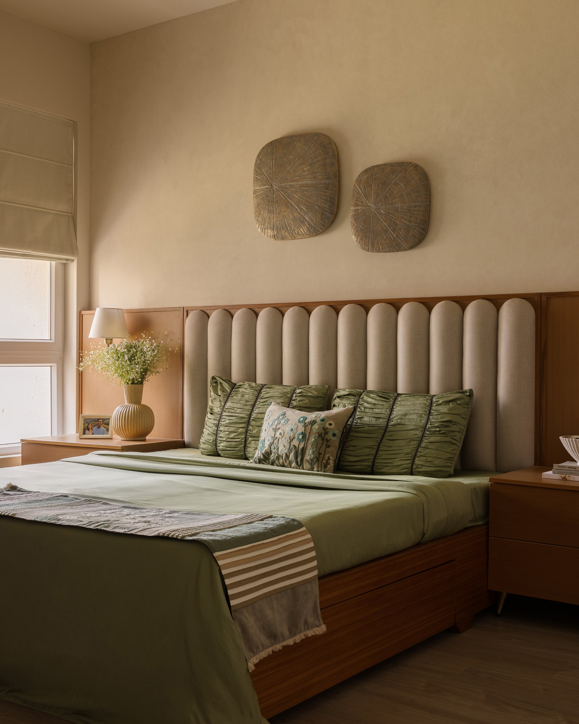 The master bedroom, where a scalloped headboard and olive linen settle into an earth-toned register