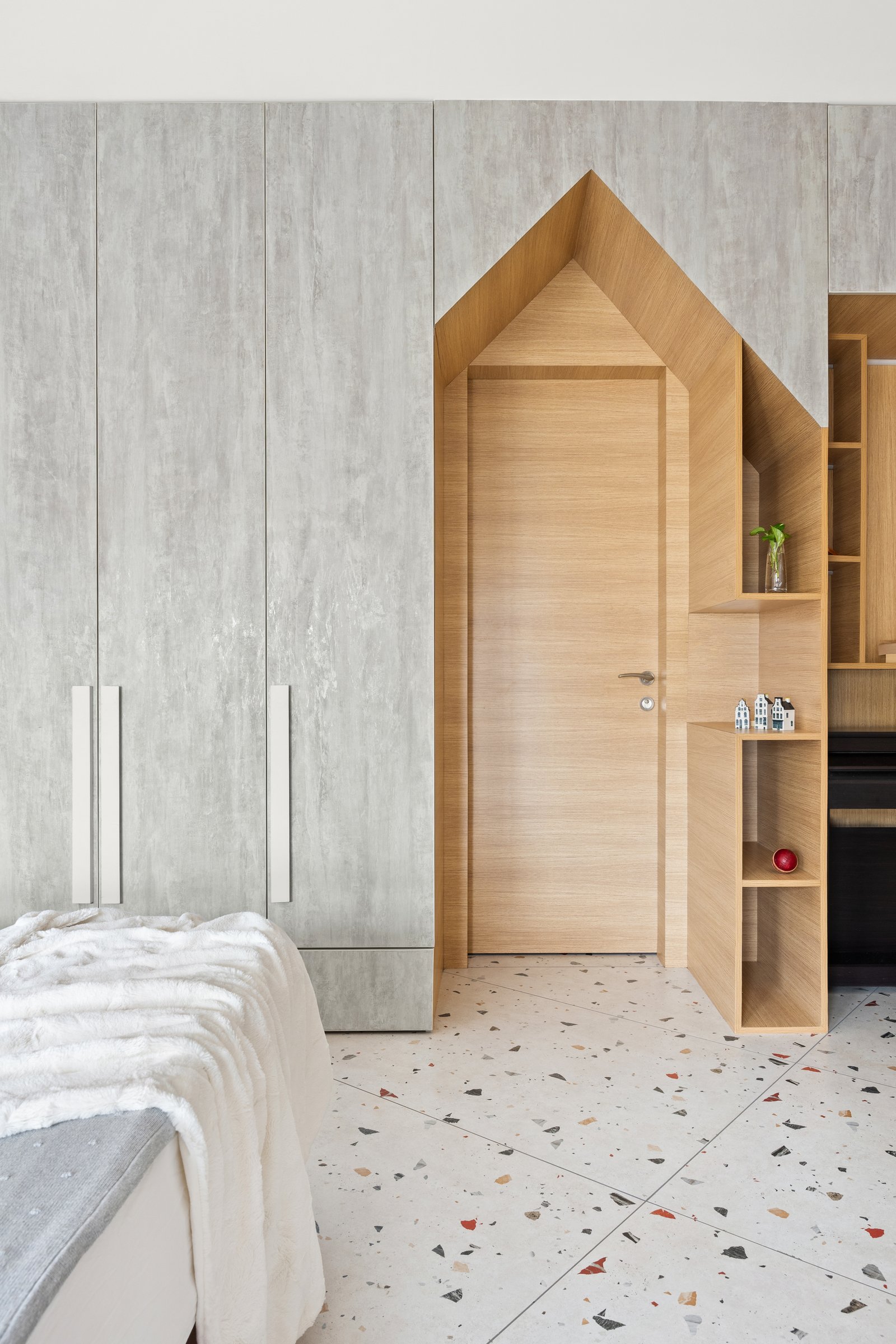 A pitched-roof opening cut into the wardrobe wall turns a routine threshold into the room's visual anchor