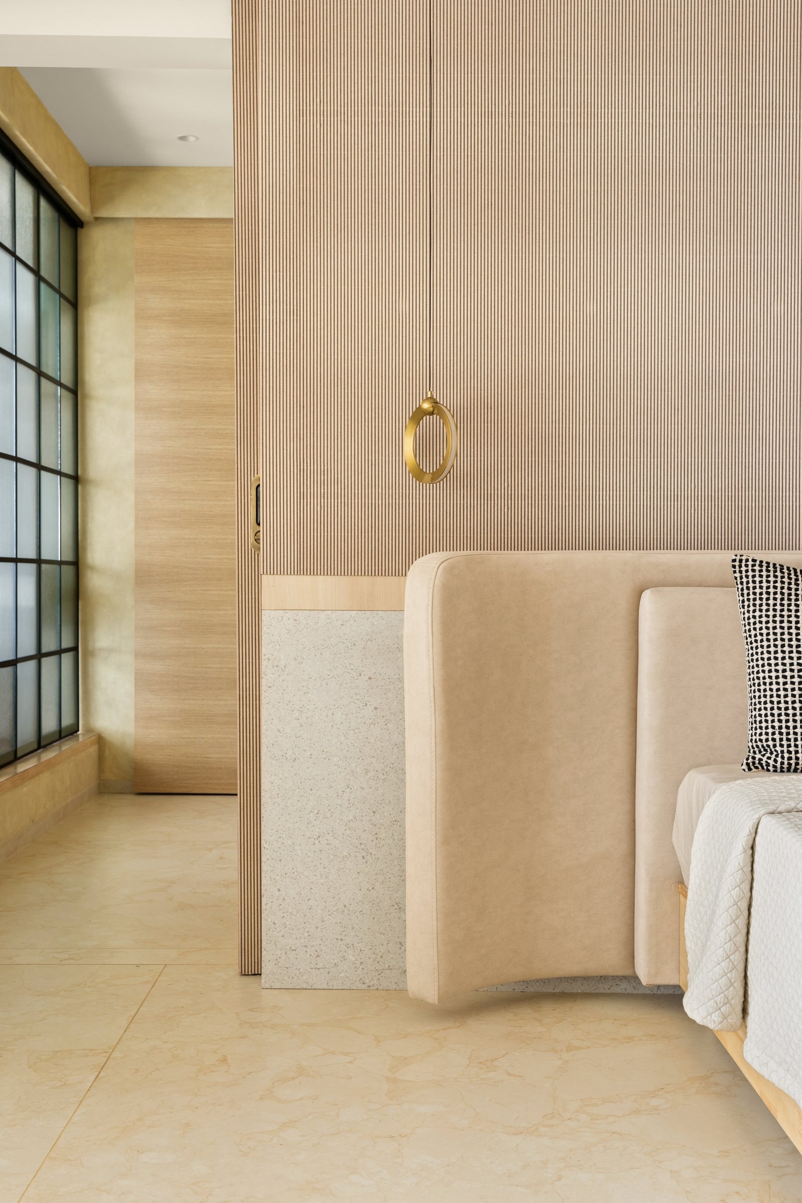 The headboard wall in close range, where brass becomes the room's signature