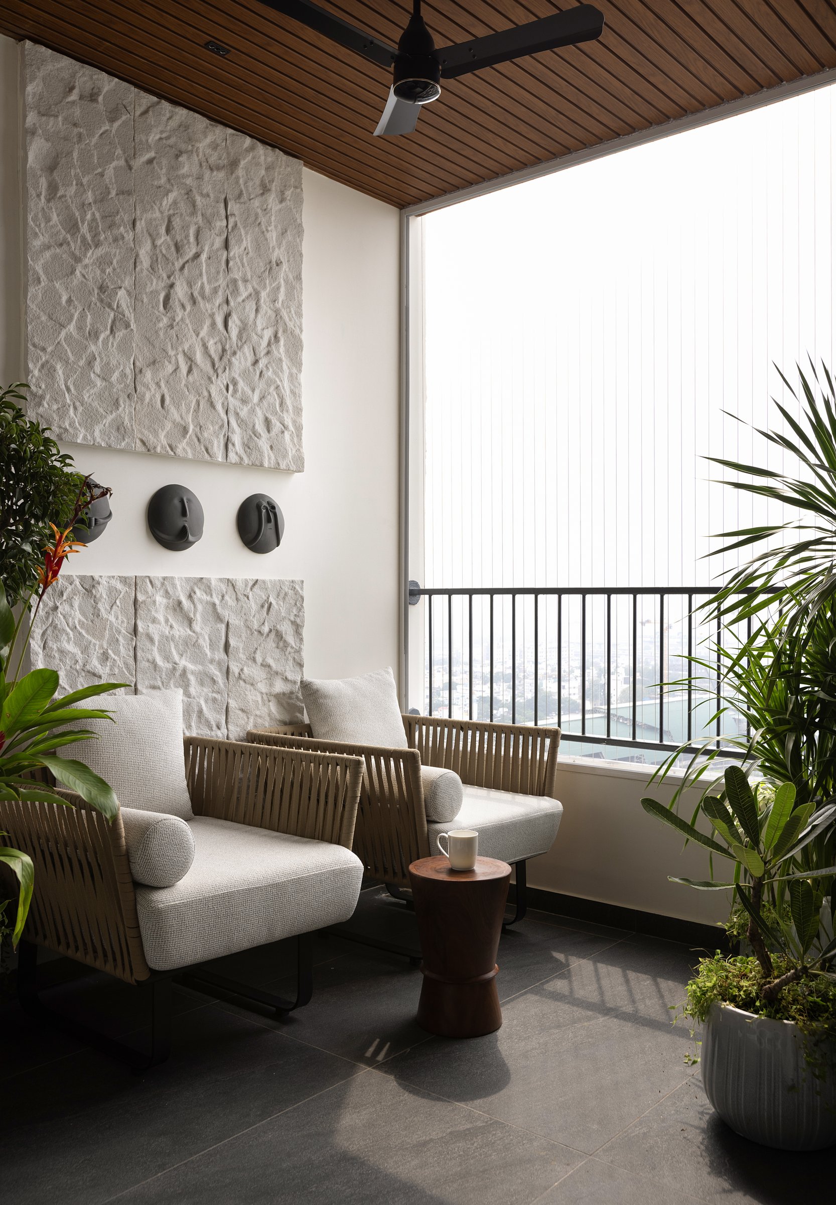 The balcony, the home's true exhale, where off-cut sandstone returns as textured wall art beneath a slatted wood ceiling