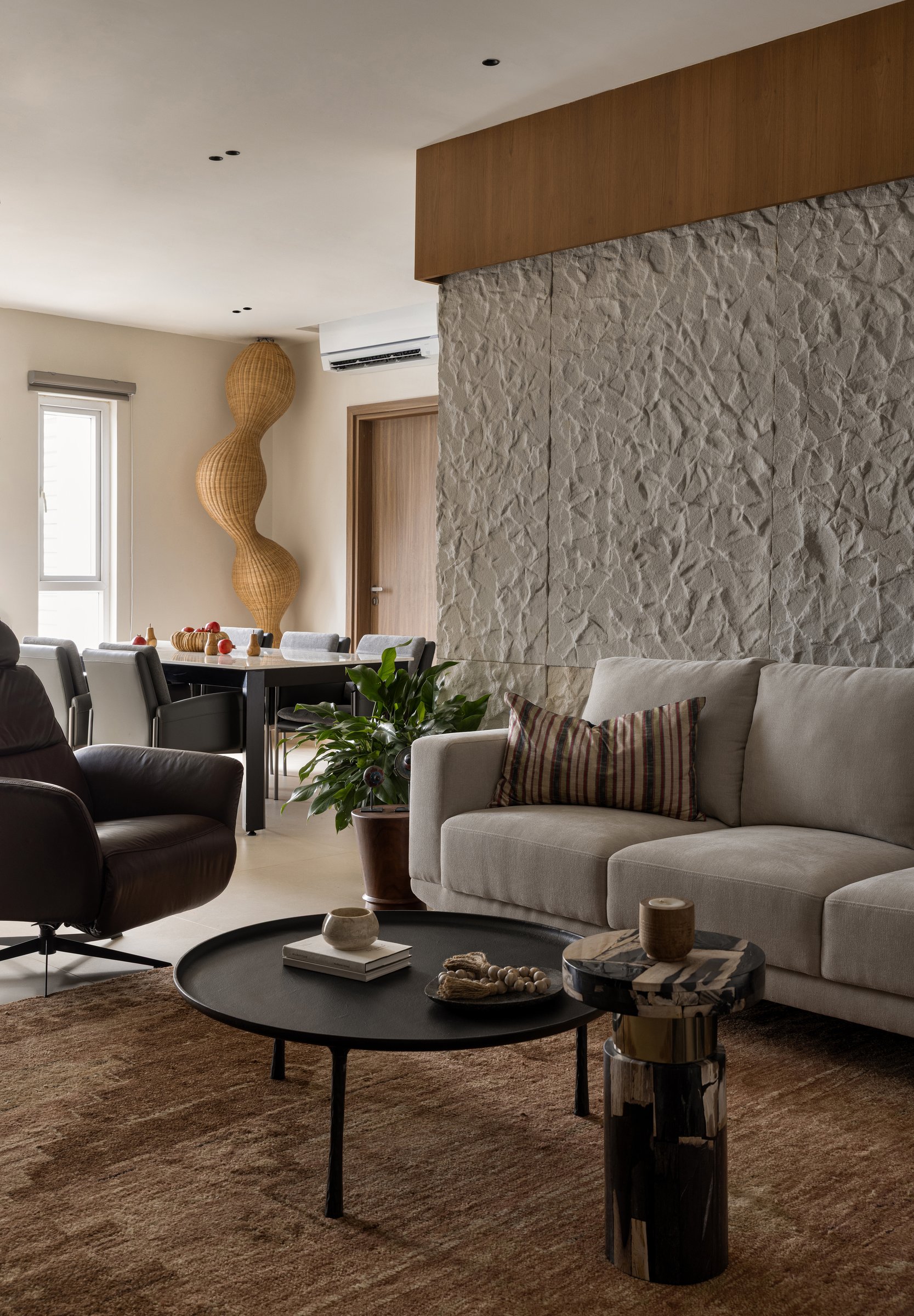 The living room, where a wall of hand-finished white sandstone holds the room together through depth rather than colour