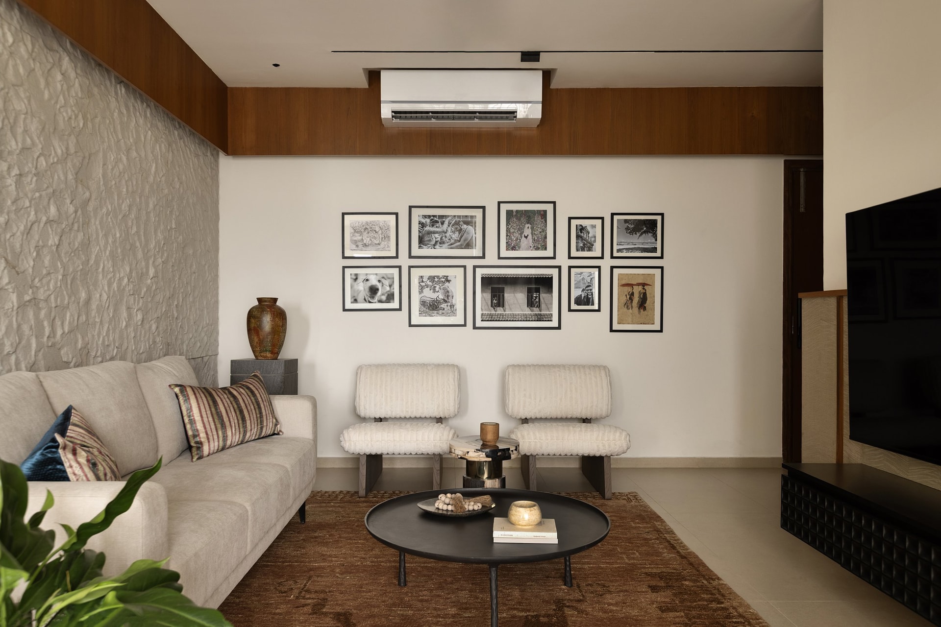 The wider living room view: stone, gallery wall, and a fossilised wood side table calibrated against one another