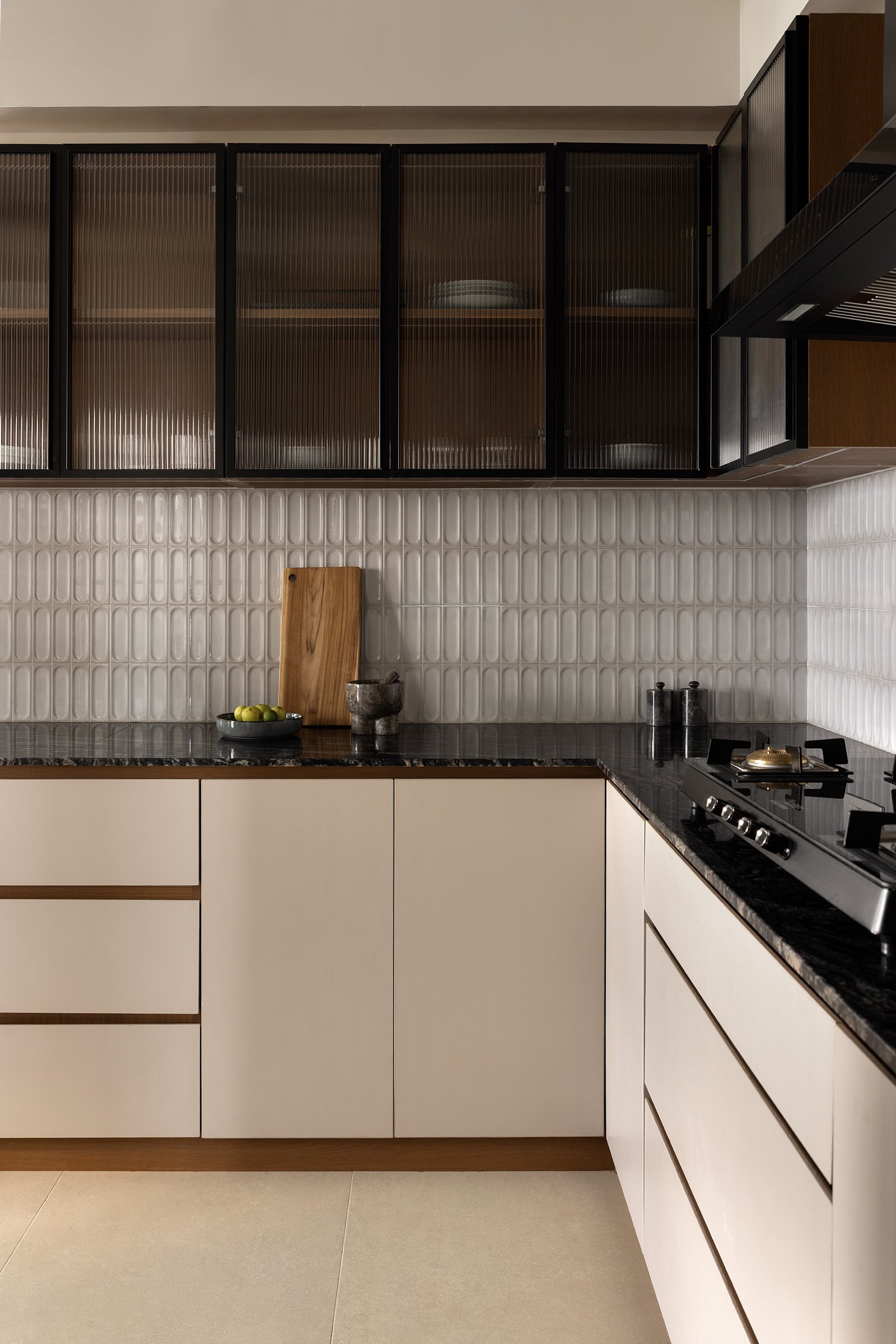 The kitchen: cream cabinetry, deep granite counters, and a ribbed white tile backsplash that catches sidelight